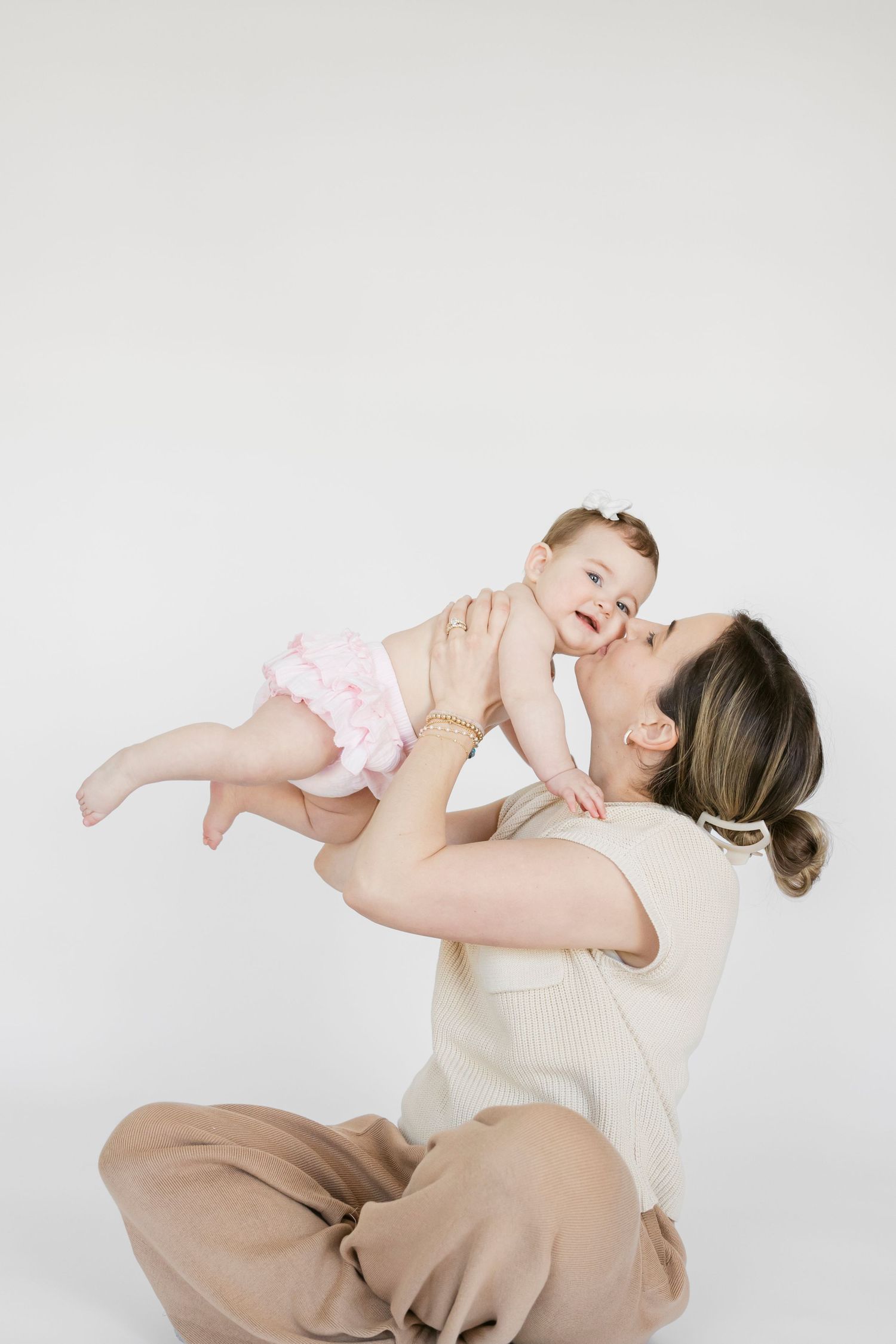 Parent and baby playing together against white studio background.
