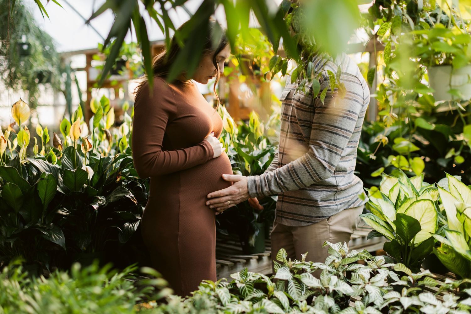 Maternity photography session in lush garden setting with natural greenery.