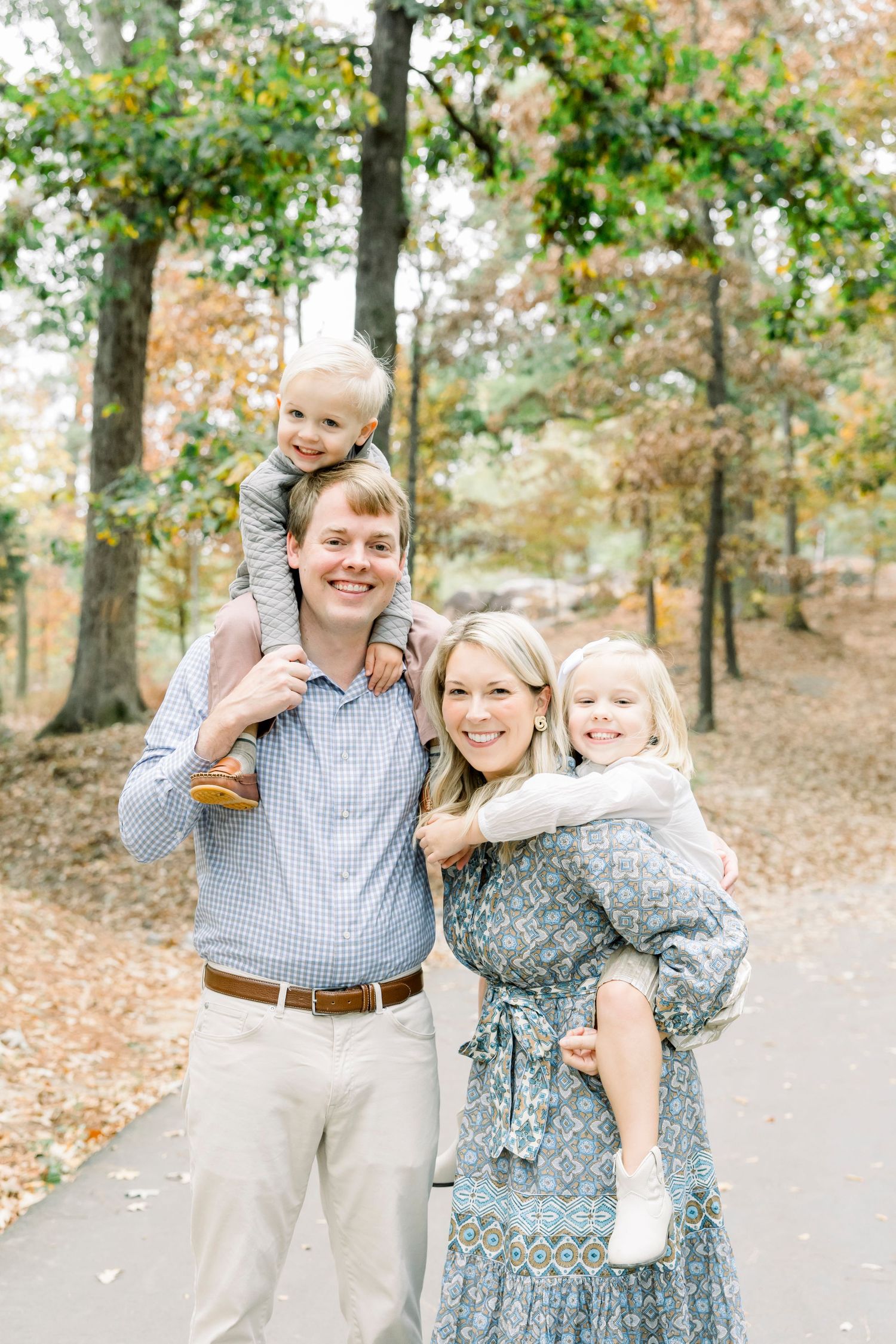 A family shares candid moments together on a leaf-covered path in autumn.