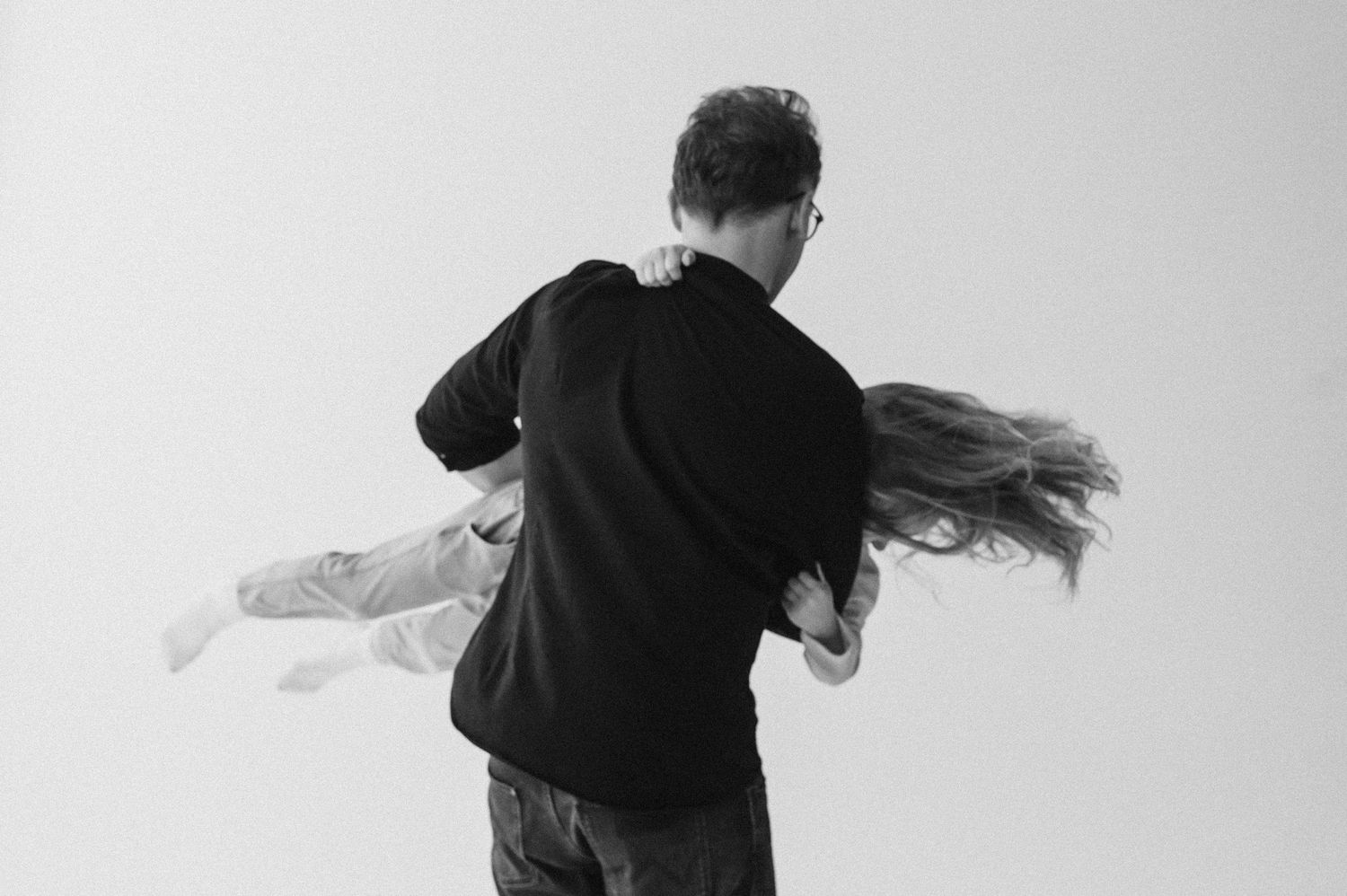 Black and white studio portraits showing playful family interactions against white background.