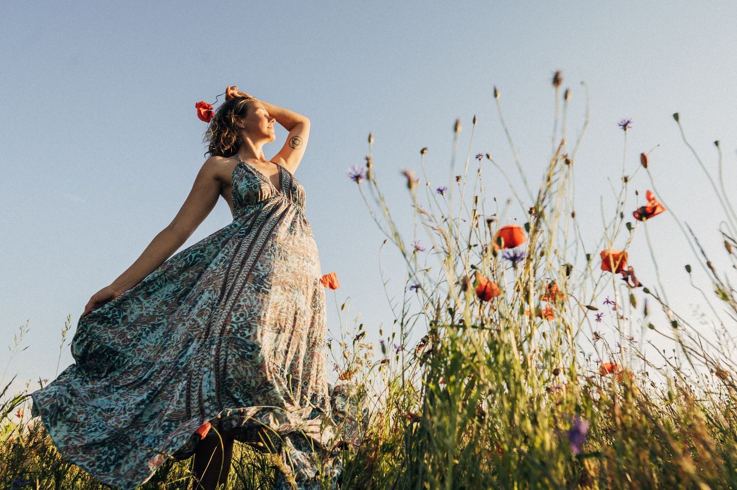 Figure in a patterned dress twirling through a meadow of summer flowers.