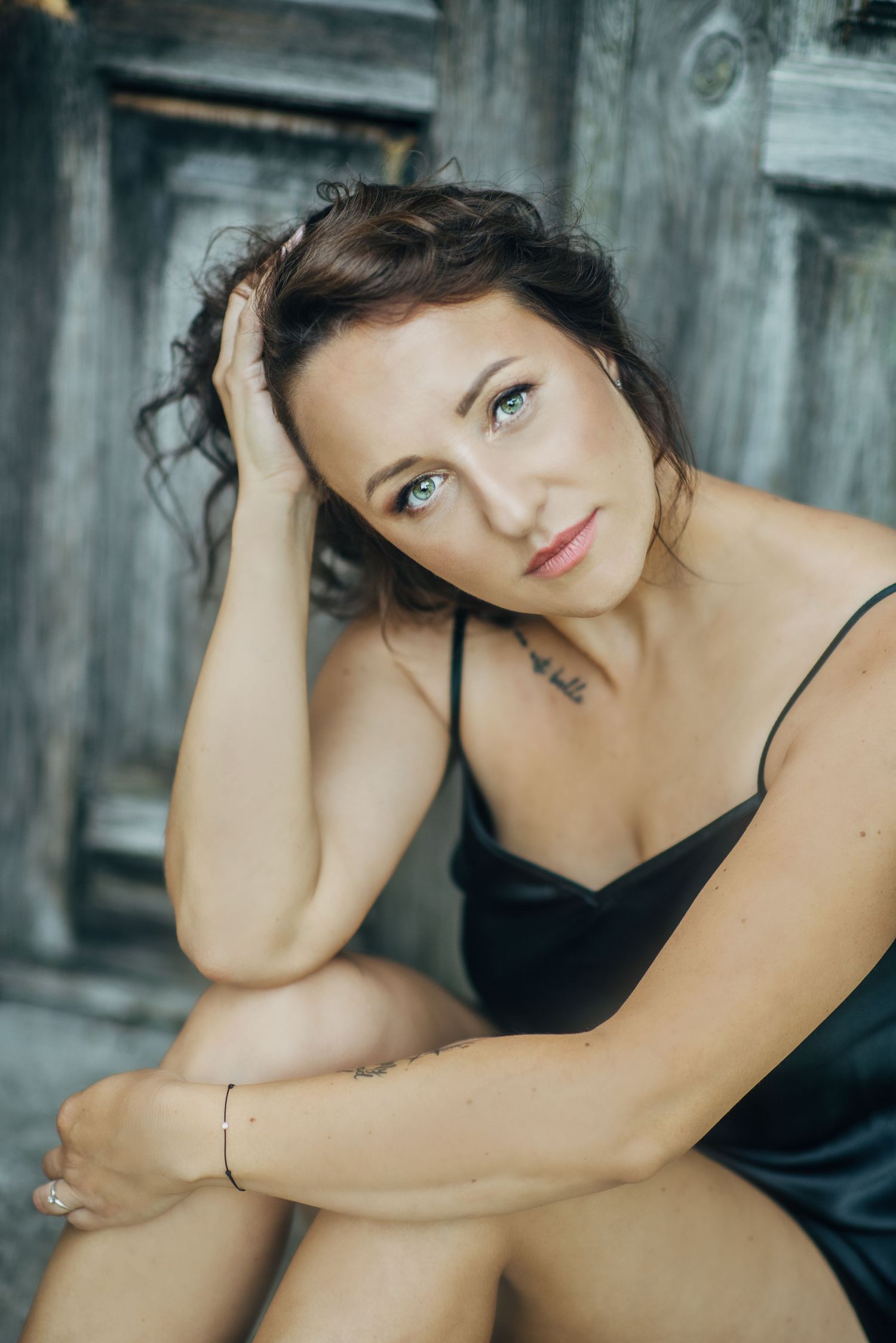 Artistic portrait against rustic grey wooden backdrop in natural lighting.