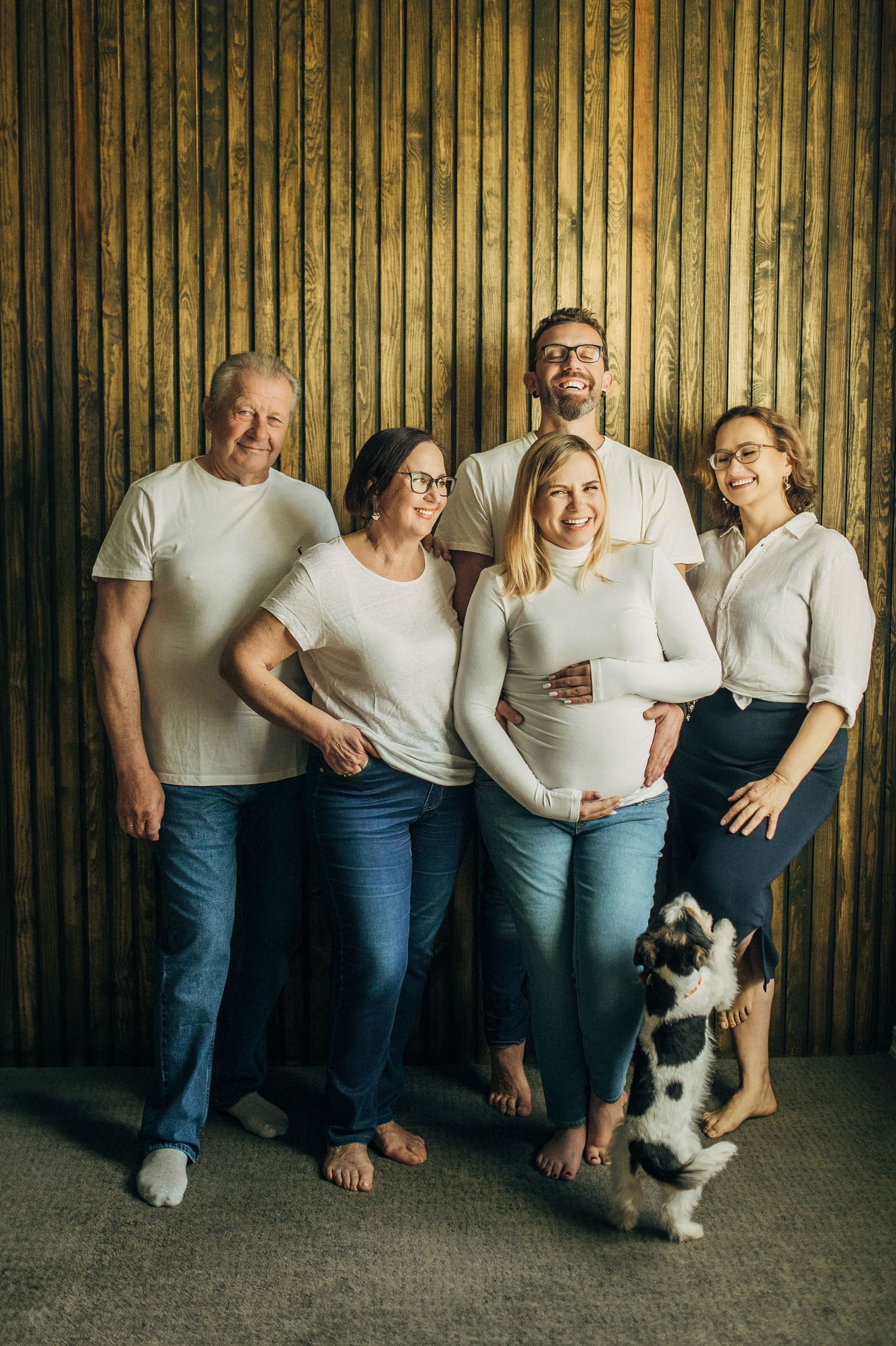Family members in matching outfits pose with their dog against a wooden panel backdrop.