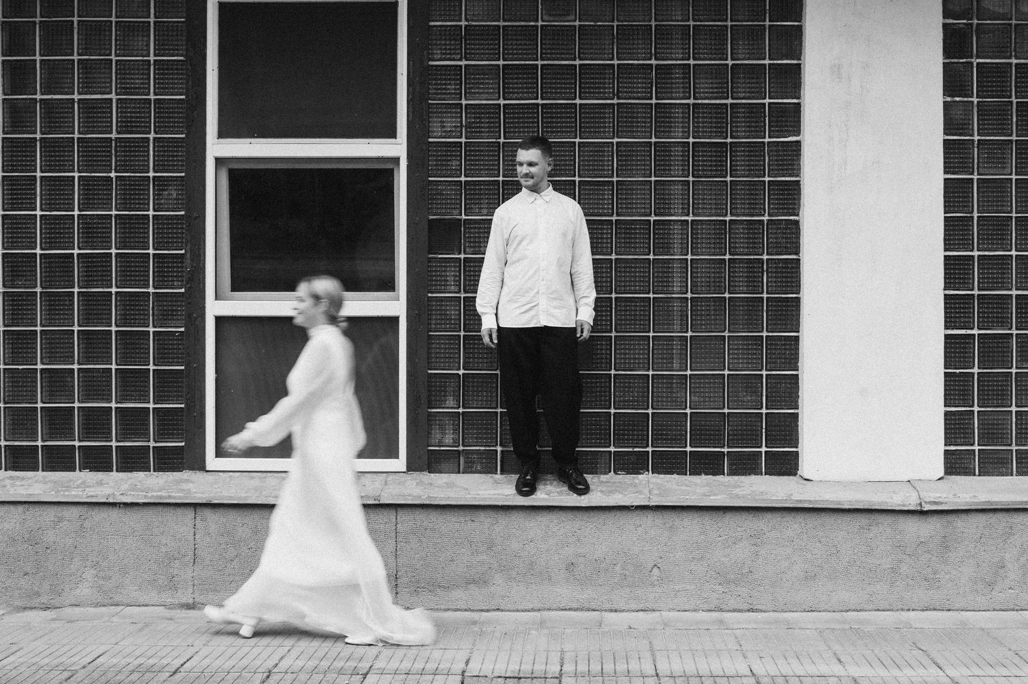 Black and white photo series showing couple dancing and twirling in front of a brick wall with windows.