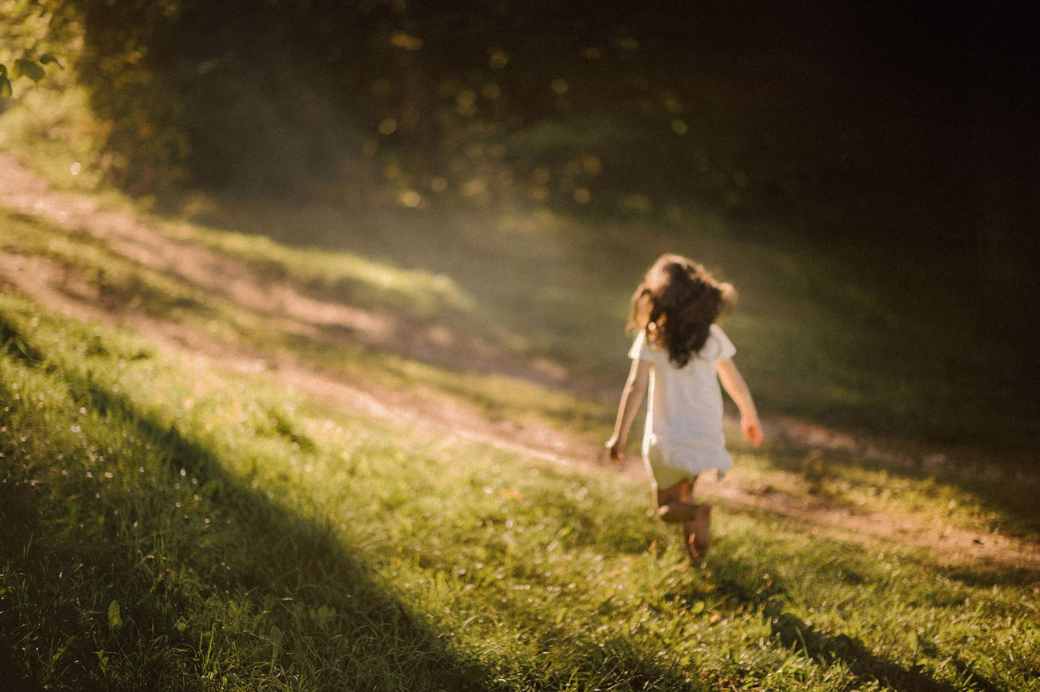Person running joyfully down a grassy hill at sunset.