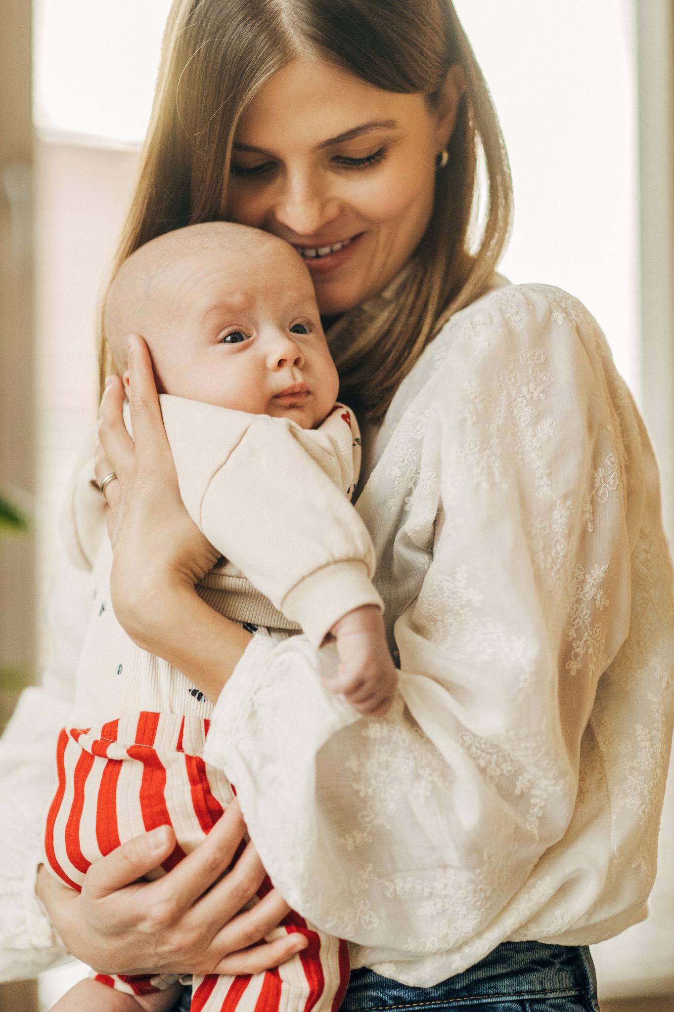 A tender moment captured between parent and baby during Christmas time near a decorated tree.
