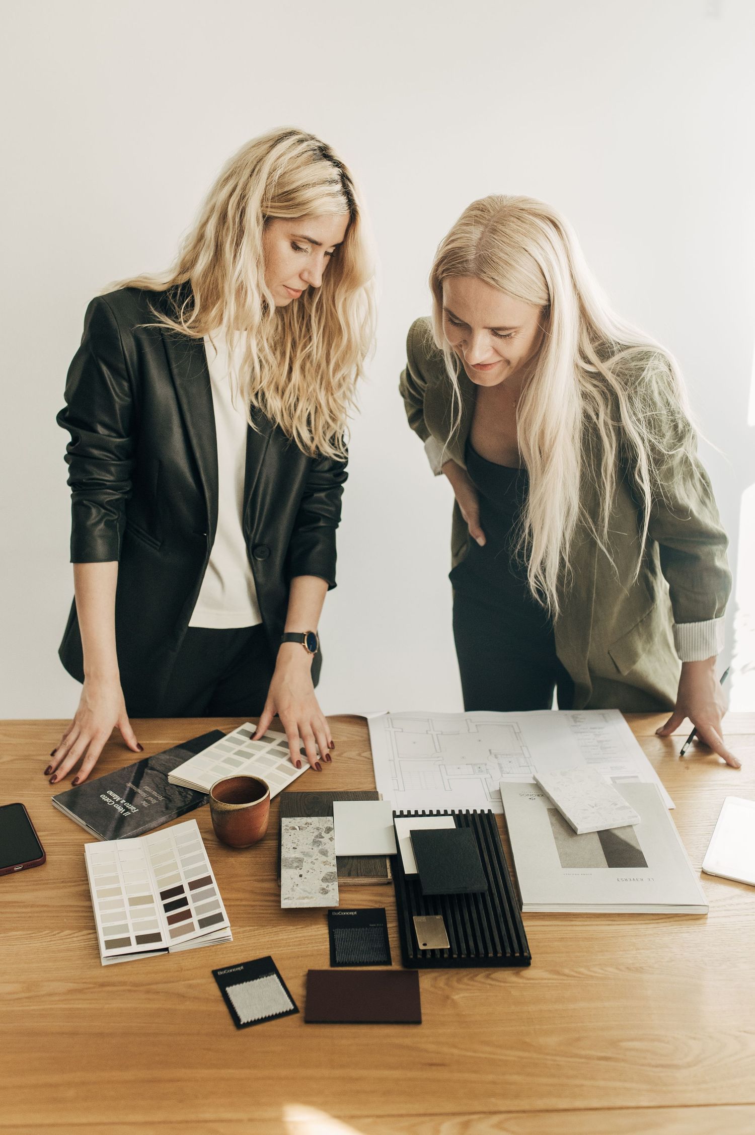 Business colleagues reviewing design samples and materials on wooden desk.