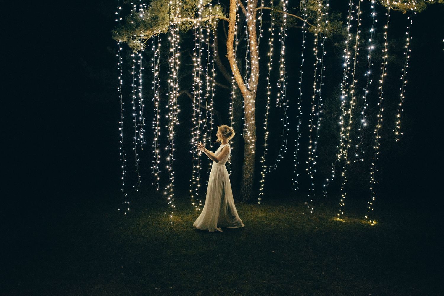 Romantic evening wedding scene with hanging string lights creating a magical backdrop.
