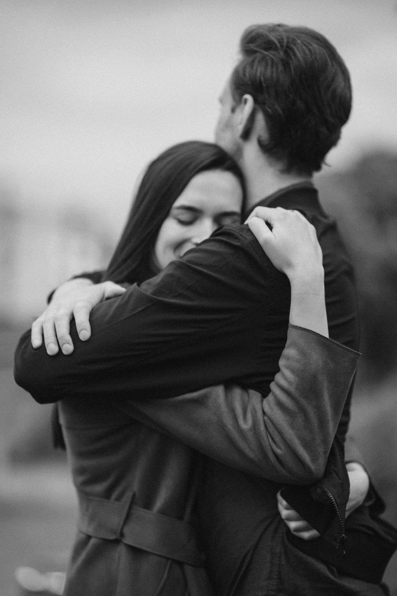 Couple embracing in emotional black and white portrait outdoors.
