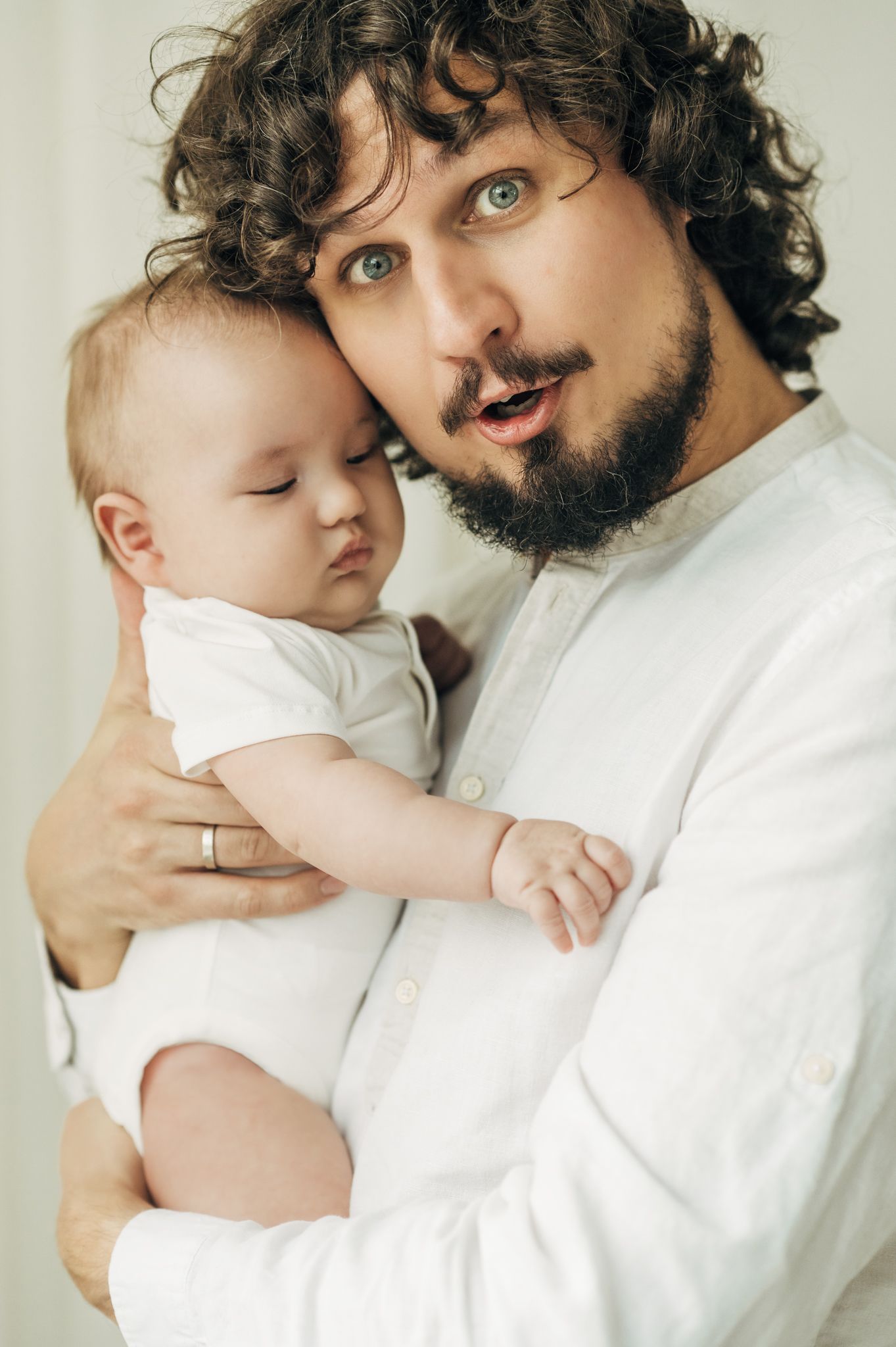 Sweet moments captured between an adult in white clothing and a baby in soft lighting.