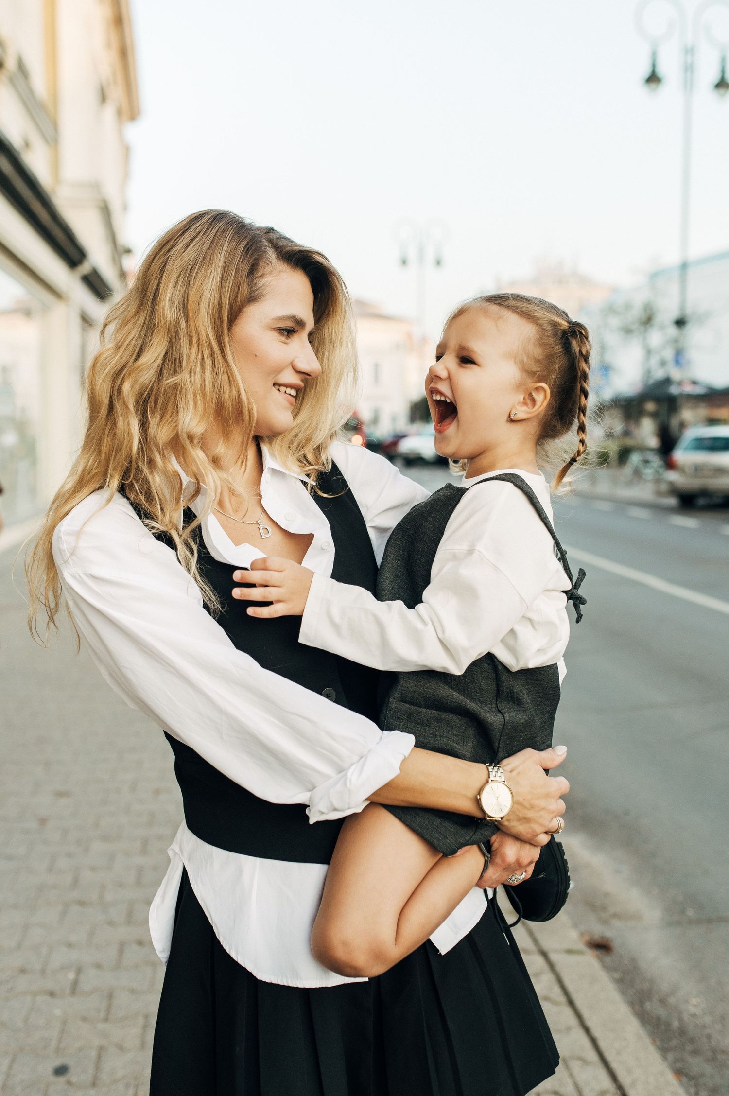 Two figures in contrasting black and white outfits sharing a joyful moment on a city street.