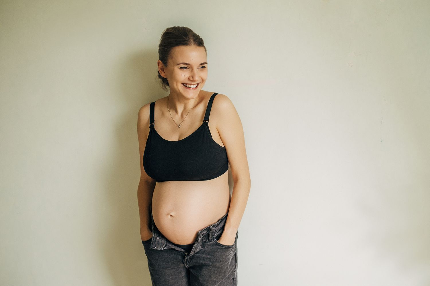 Minimalist maternity portraits against a light wall showing pregnancy progression.