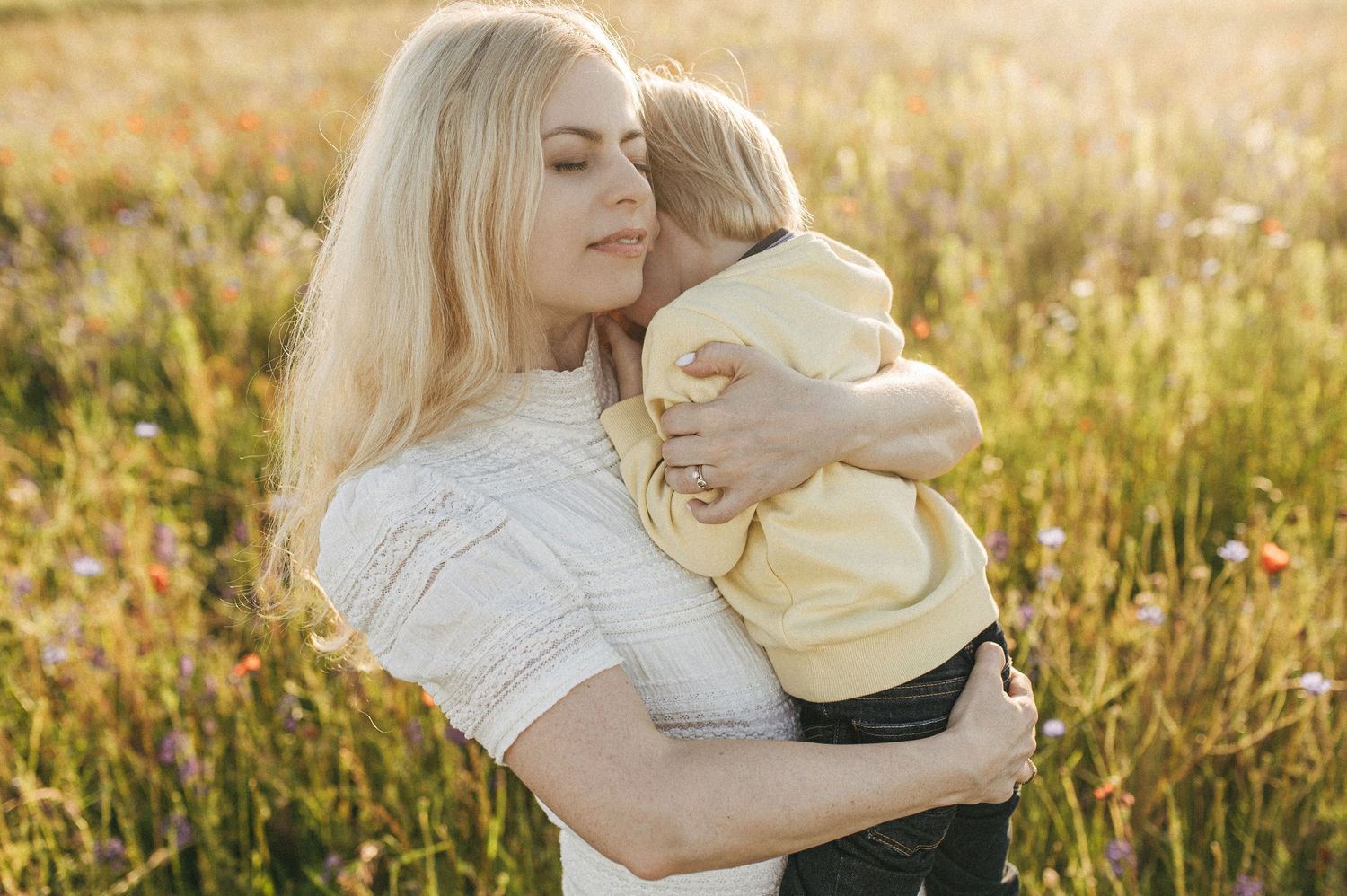 Intimate family moment captured in golden sunlit field at sunset.