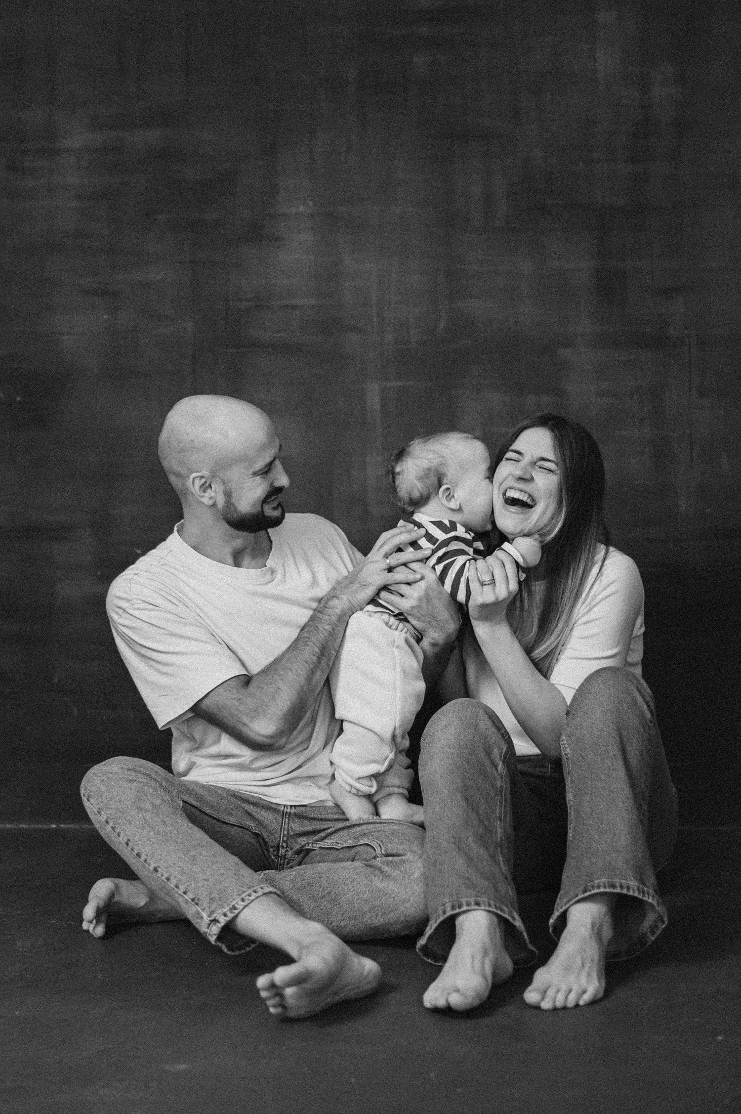 Black and white portrait of a joyful family moment on dark background.