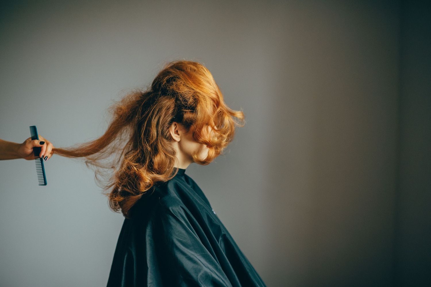 Hair styling motion shot with flowing blonde hair against neutral background.