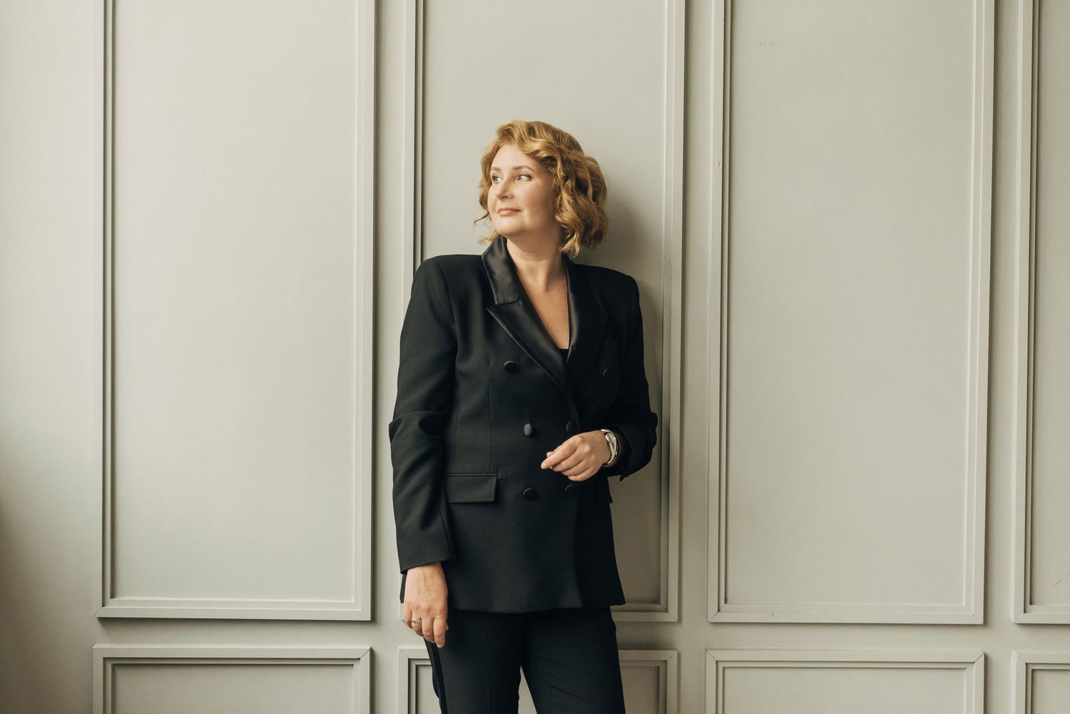 Professional fashion portraits against grey paneled wall in business attire.