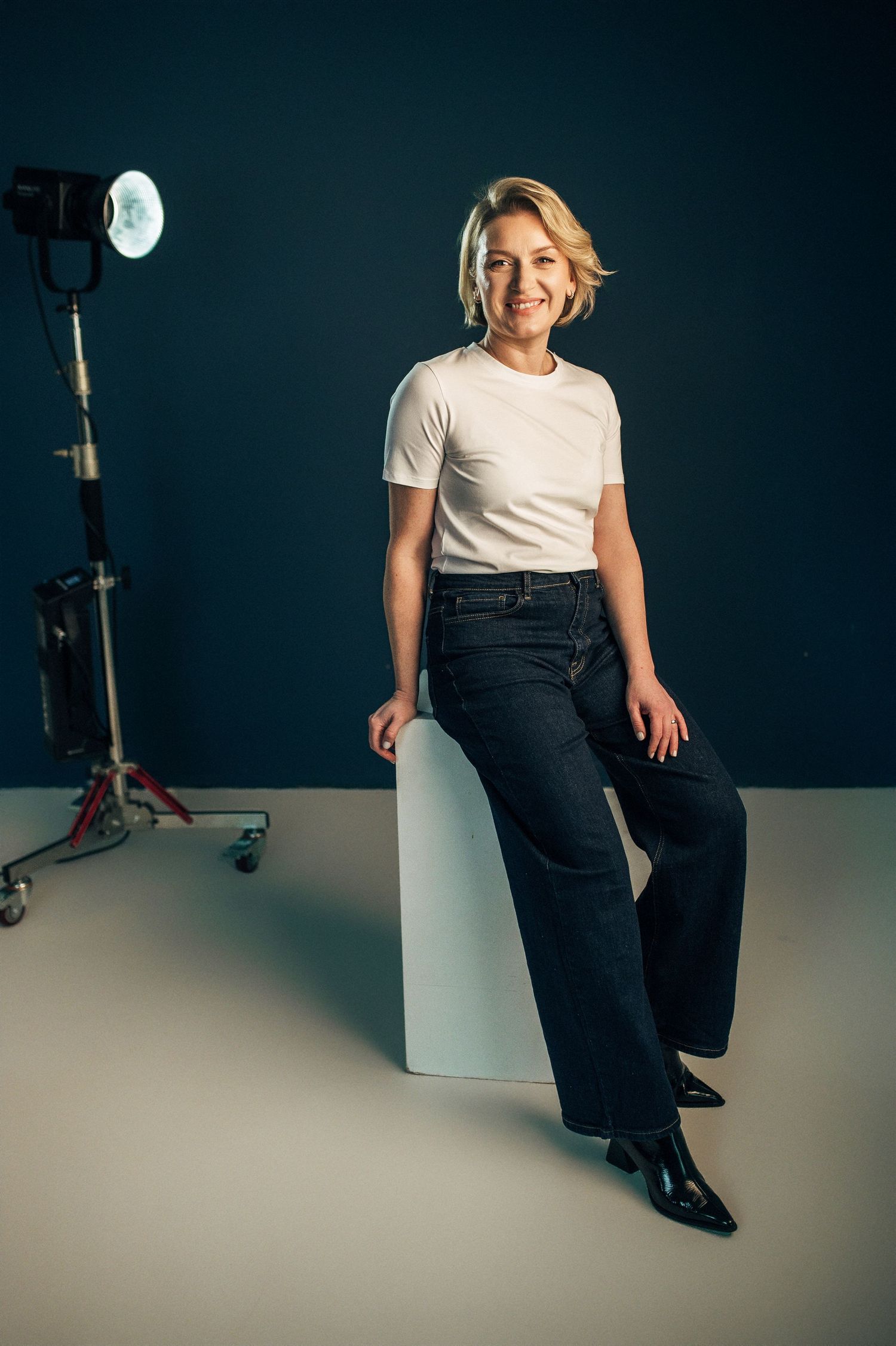 A person in a white t-shirt and dark pants poses against a dark wall in a series of dynamic seated positions.