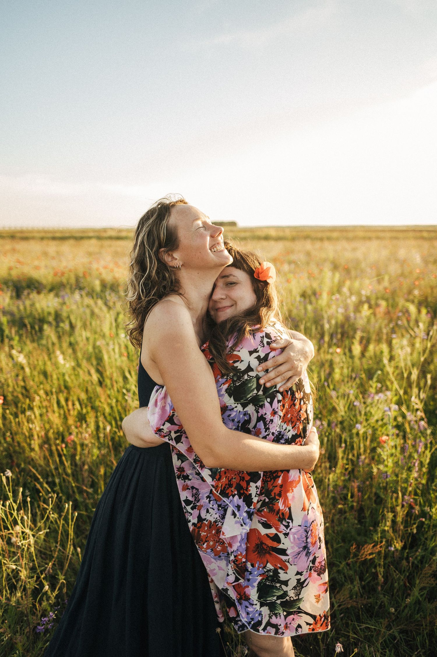 Emotional embrace captured in flowery field during sunset.