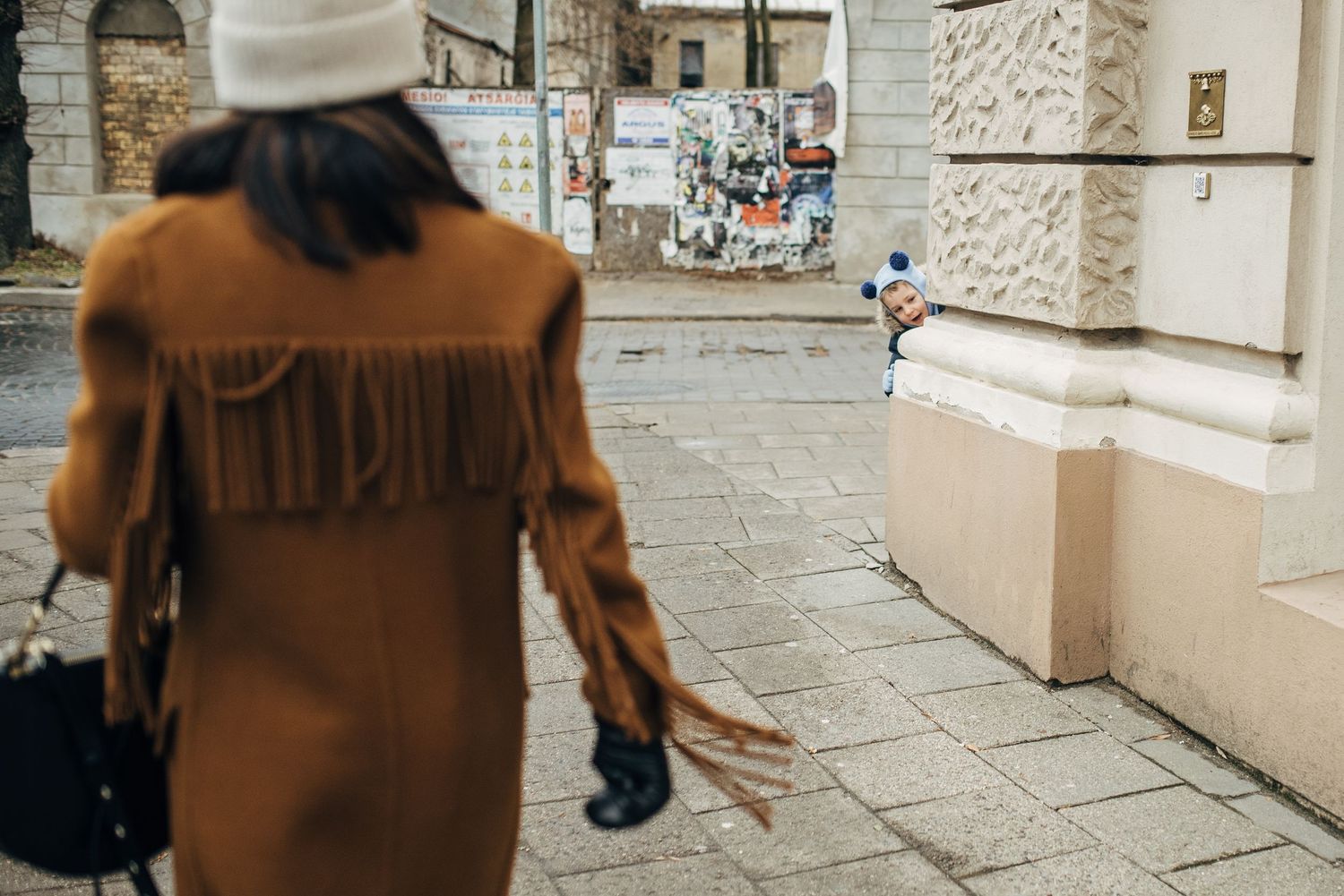 People walking past stone buildings wearing casual autumn clothing.