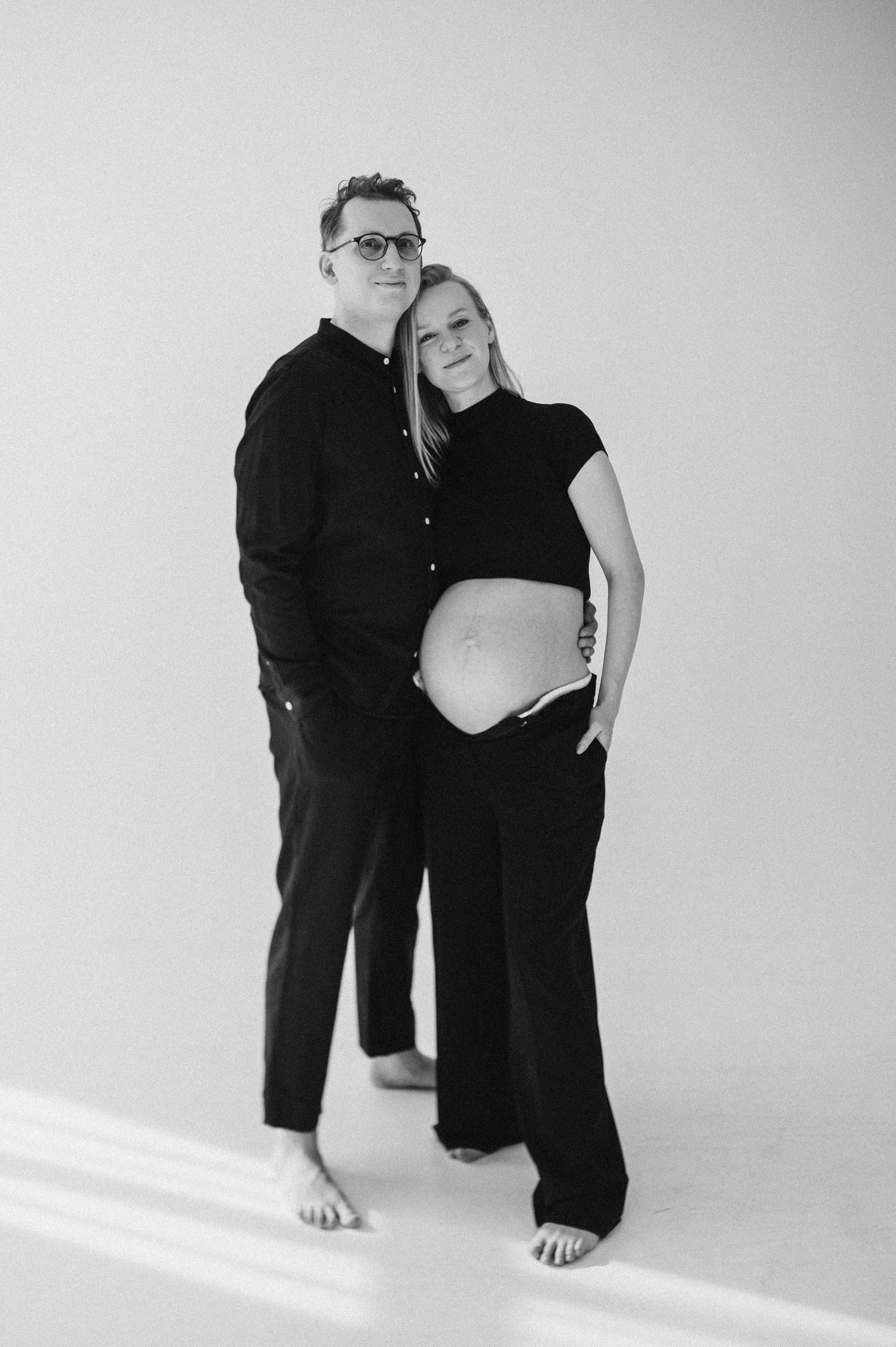 Minimalist black and white maternity portraits showing couple in casual attire.