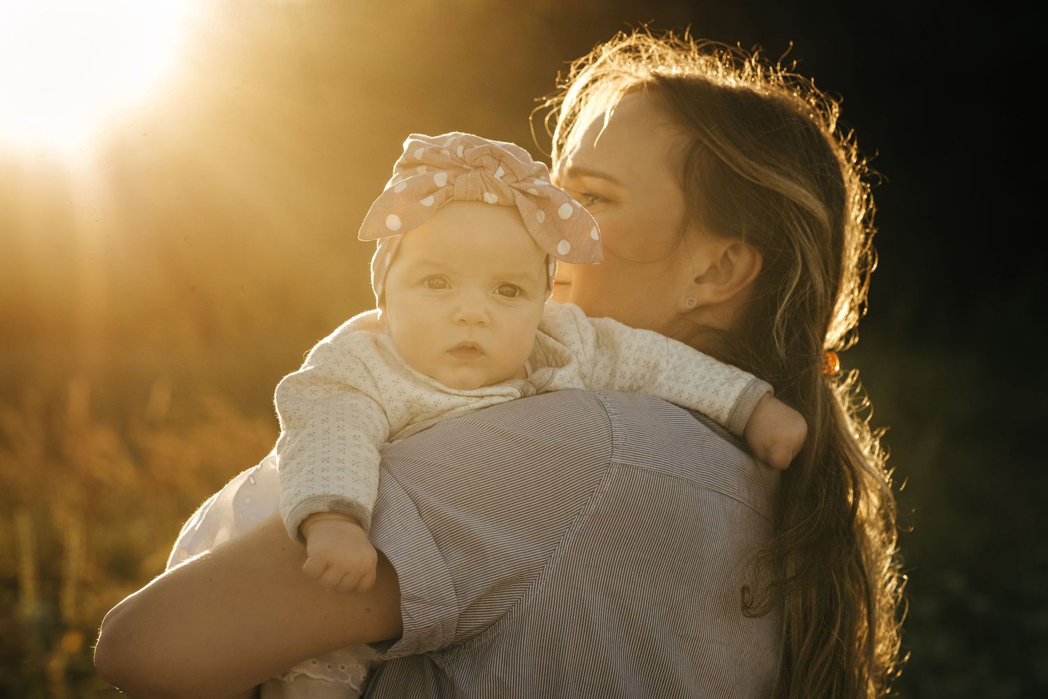 Warm golden sunlight illuminates figures embracing against a dark background.
