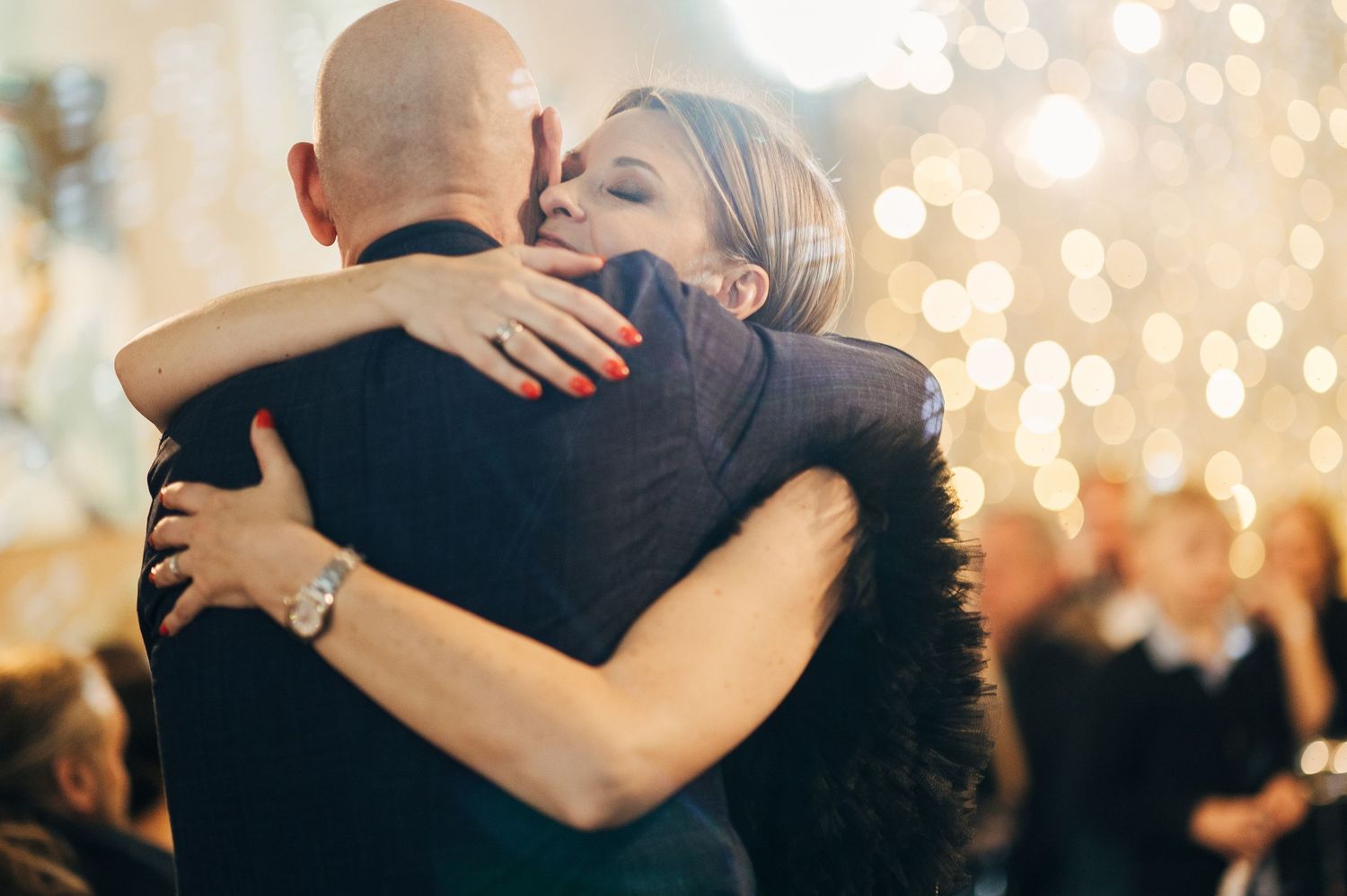 Couples dancing together under romantic string lights at an evening celebration.