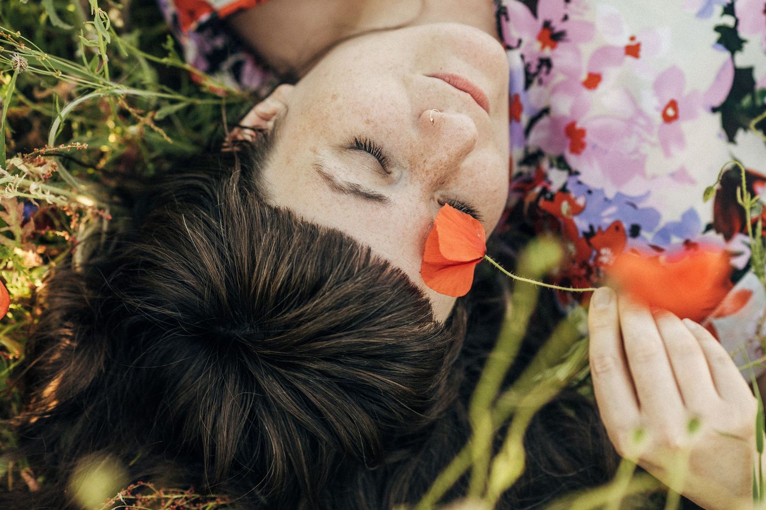A dreamy summer scene with someone lying in a wildflower meadow wearing floral prints.