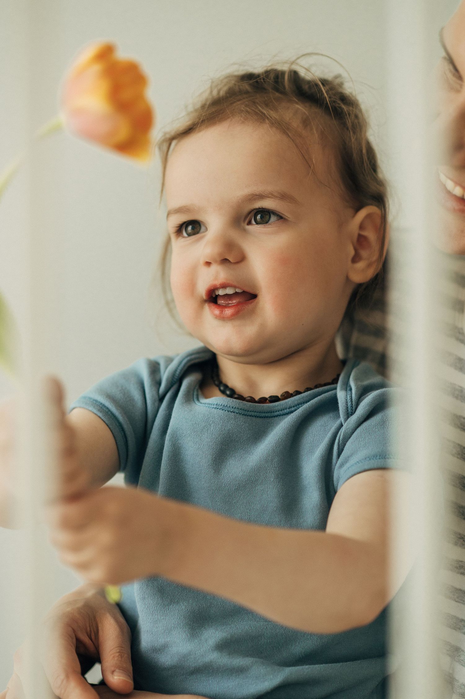 Candid photos of a toddler in a blue shirt playing and smiling through crib bars.