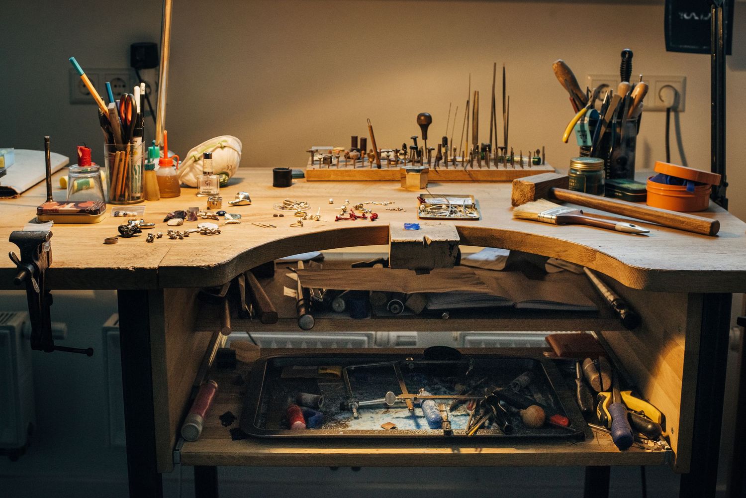 Overhead view of a workbench filled with jewelry making tools and supplies in a studio.
