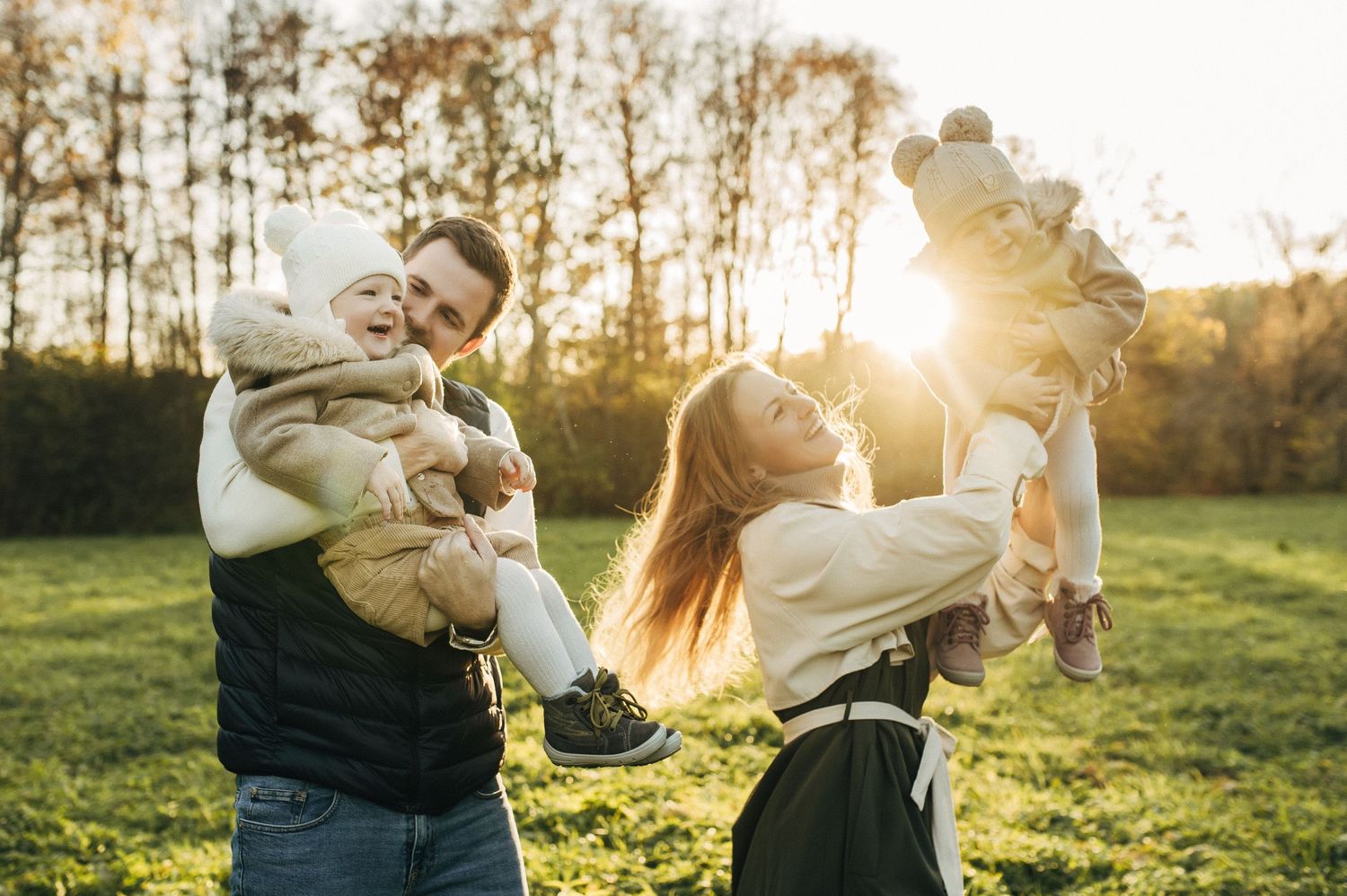 Outdoor family photoshoot silhouettes against golden sunset in grassy field.