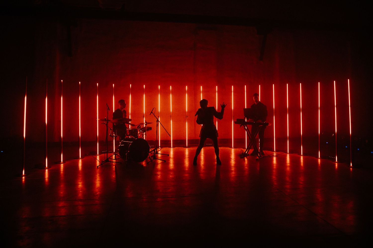 Red illuminated vertical light bars create a dramatic architectural display in a dark space.