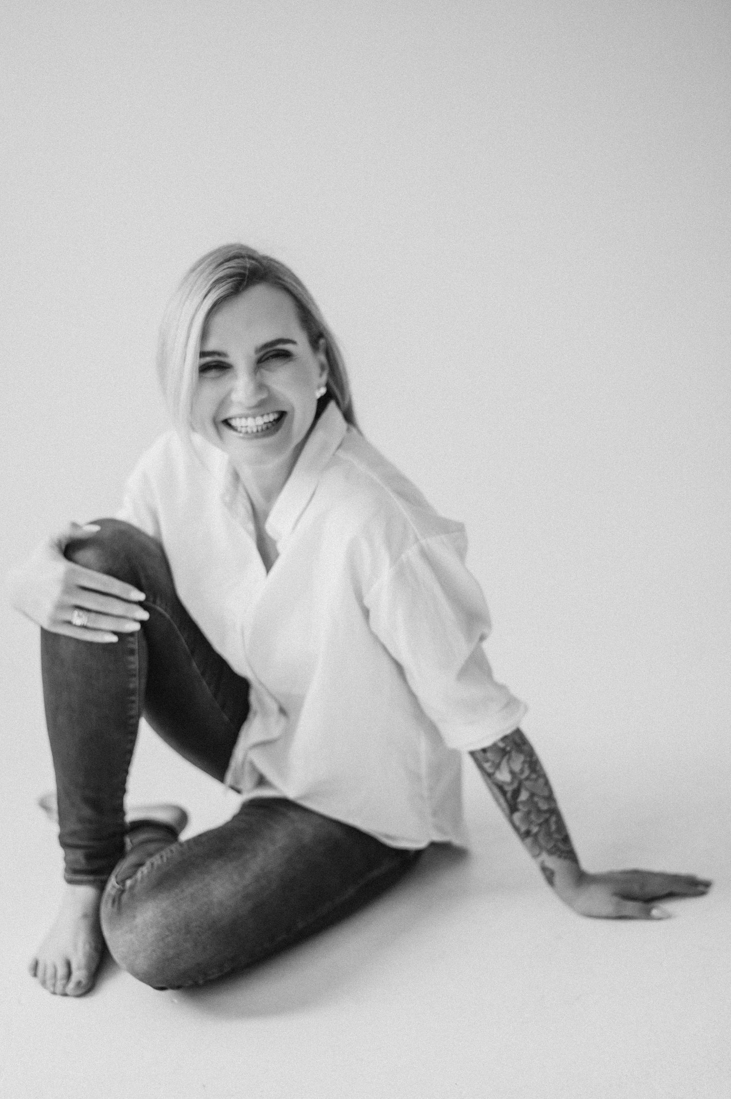 Person in white top and jeans laying playfully on white floor showing various poses.