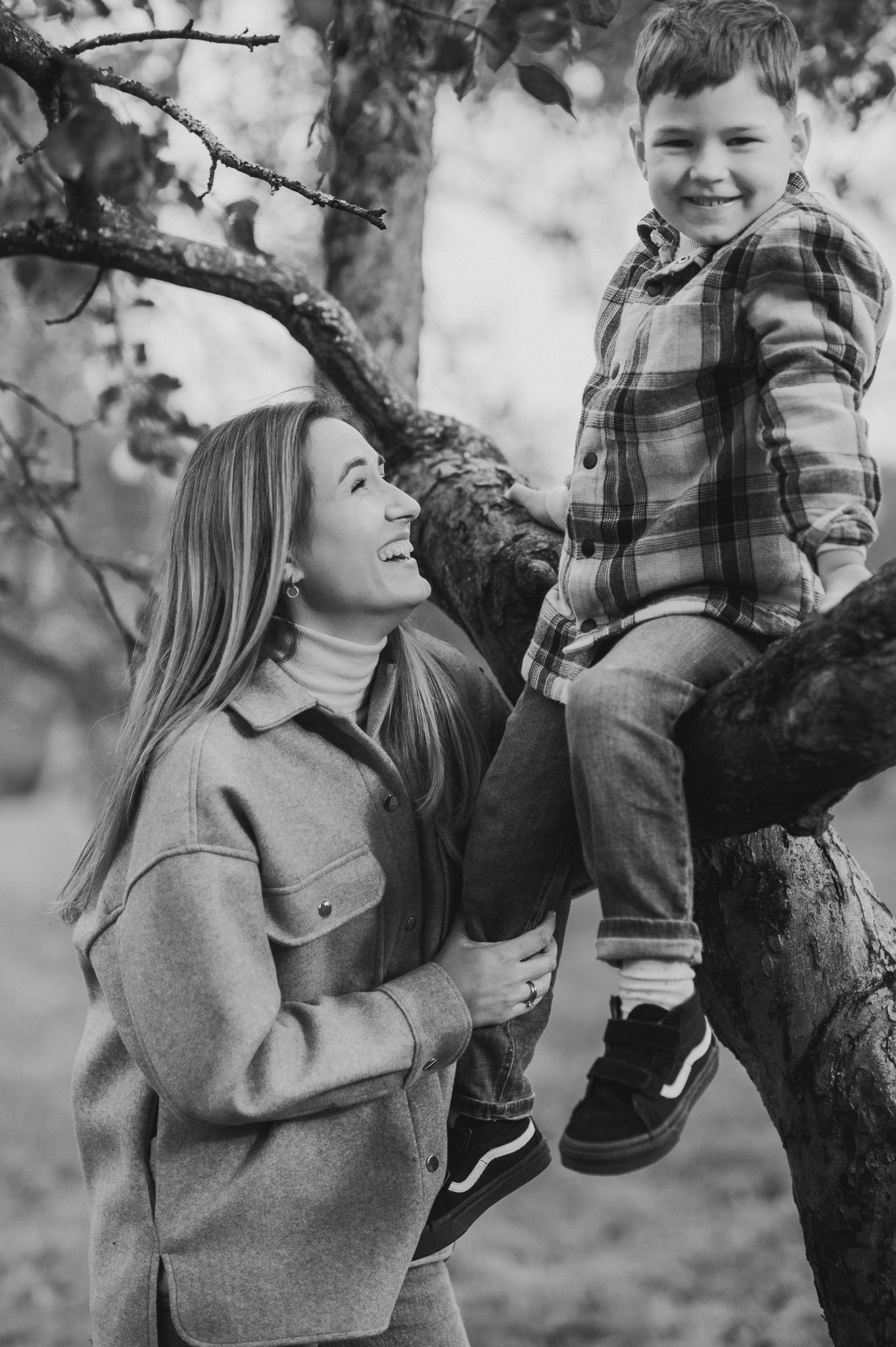An autumn outdoor portrait of parent and child by a tree.