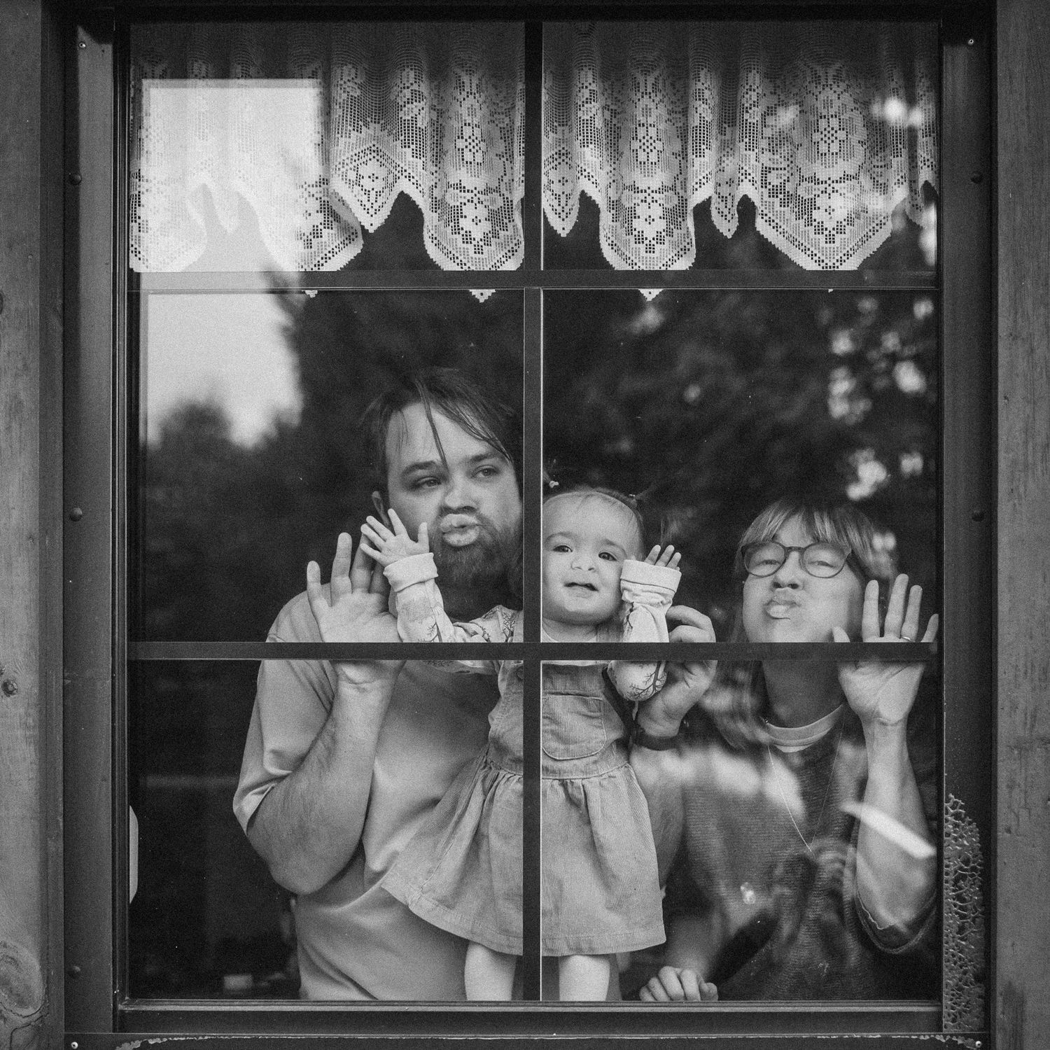 Children press their faces against a school bus window making silly expressions.