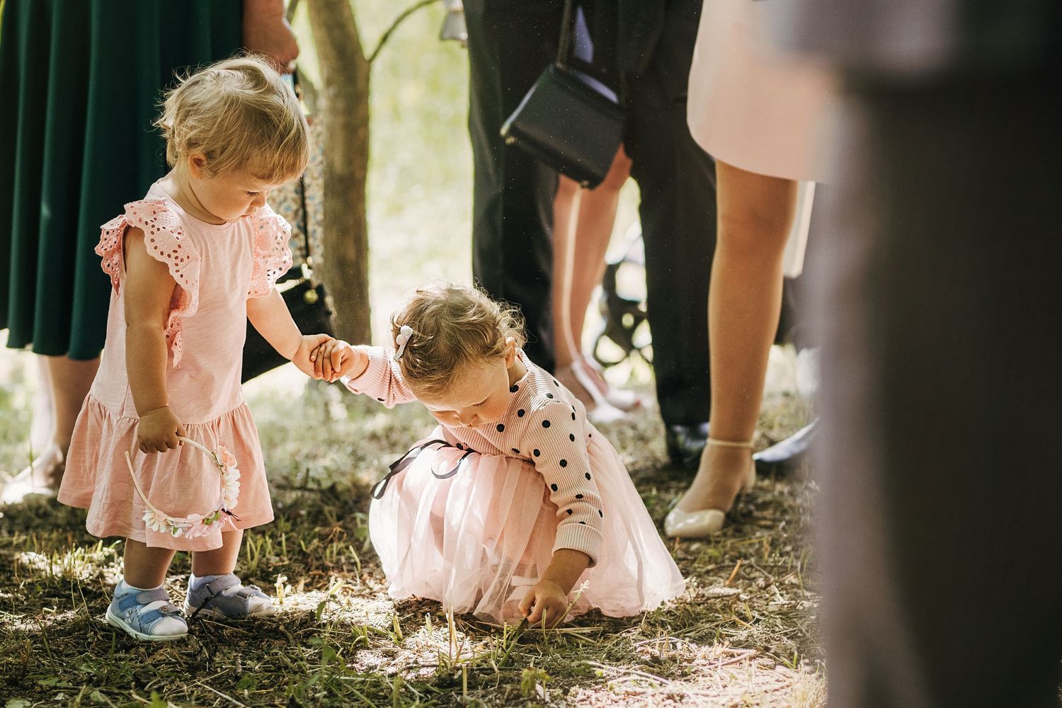Two little girls in pink dresses playing outdoors at a wedding celebration.