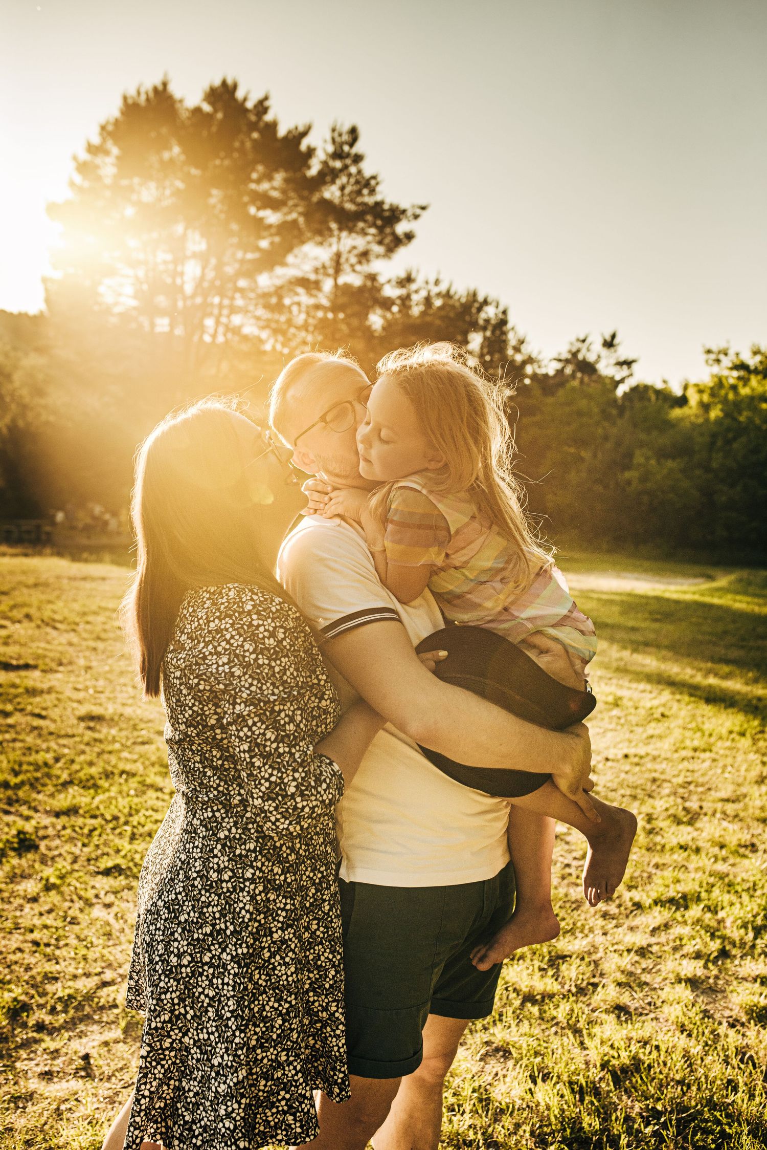 A family sharing an intimate moment in golden sunset light outdoors.