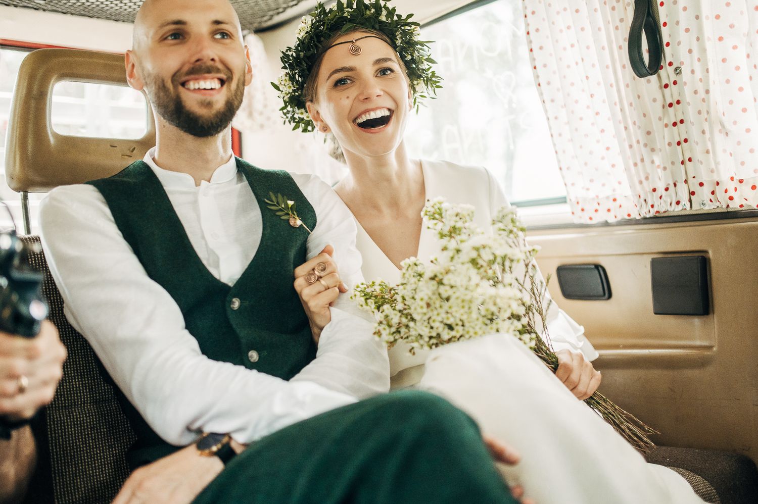 Happy couple wearing floral crown laughs together in vintage setting.