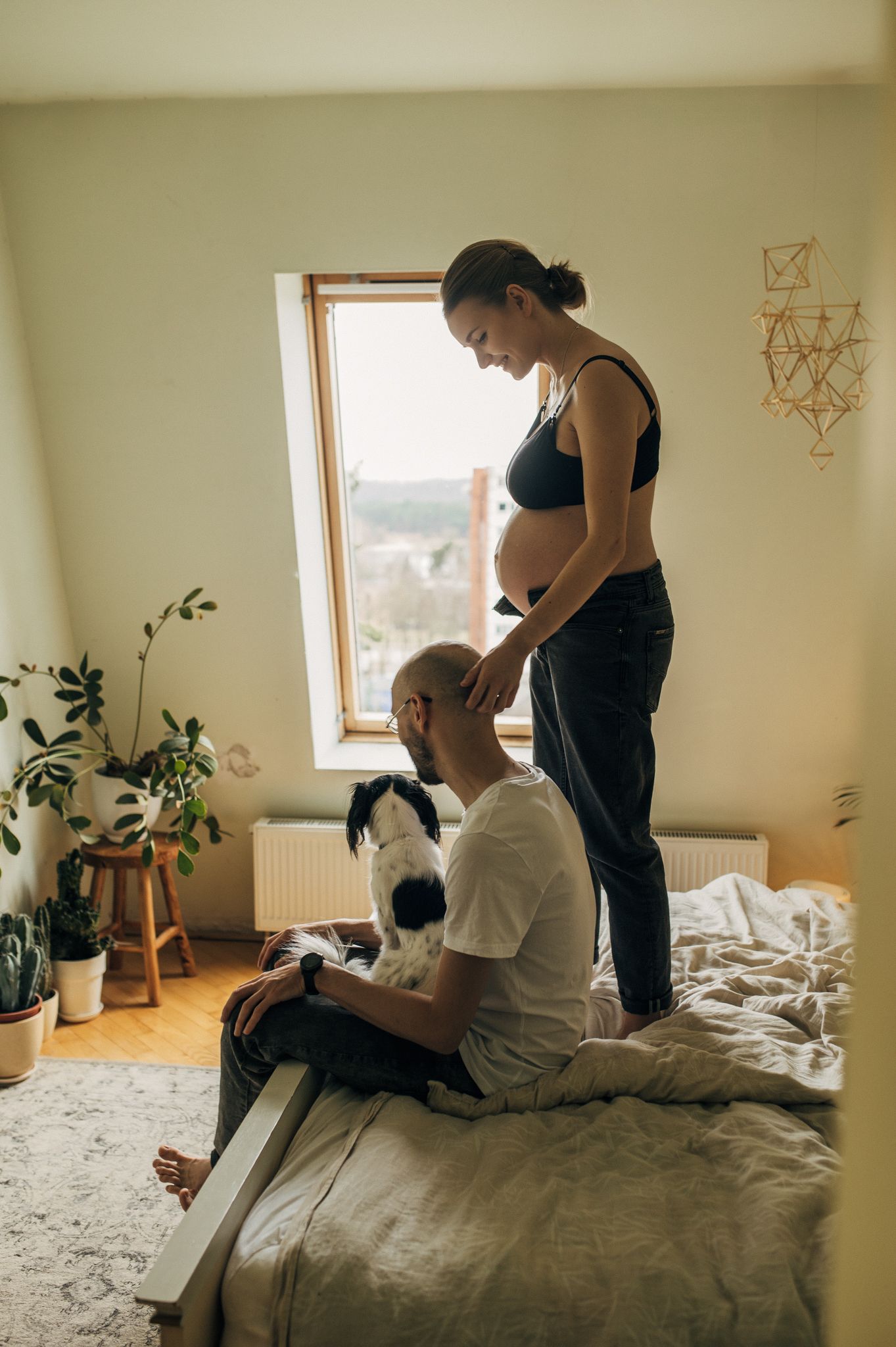 Casual indoor maternity session with natural window light and house plants.