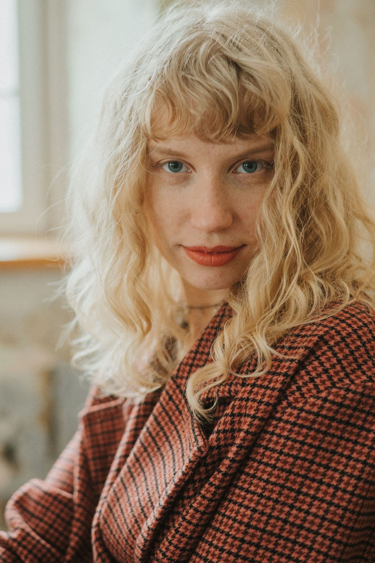 Portrait in soft natural light showcasing wavy blonde hair and vintage style clothing.