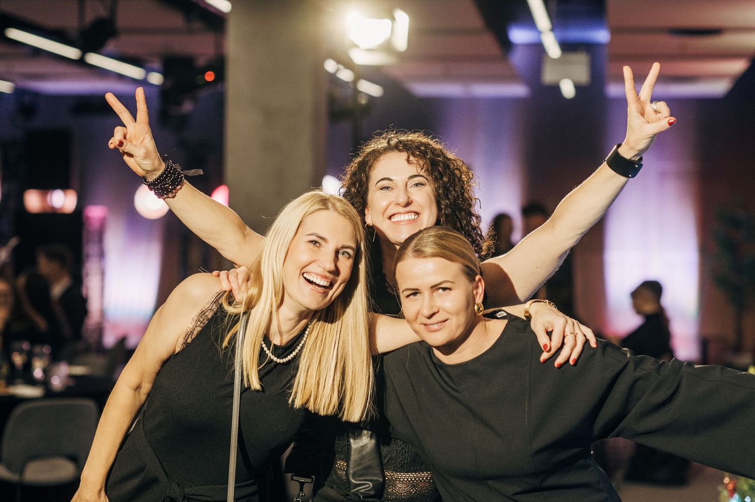 People celebrating and dancing together at a lively indoor event with colorful lighting and joyful expressions.