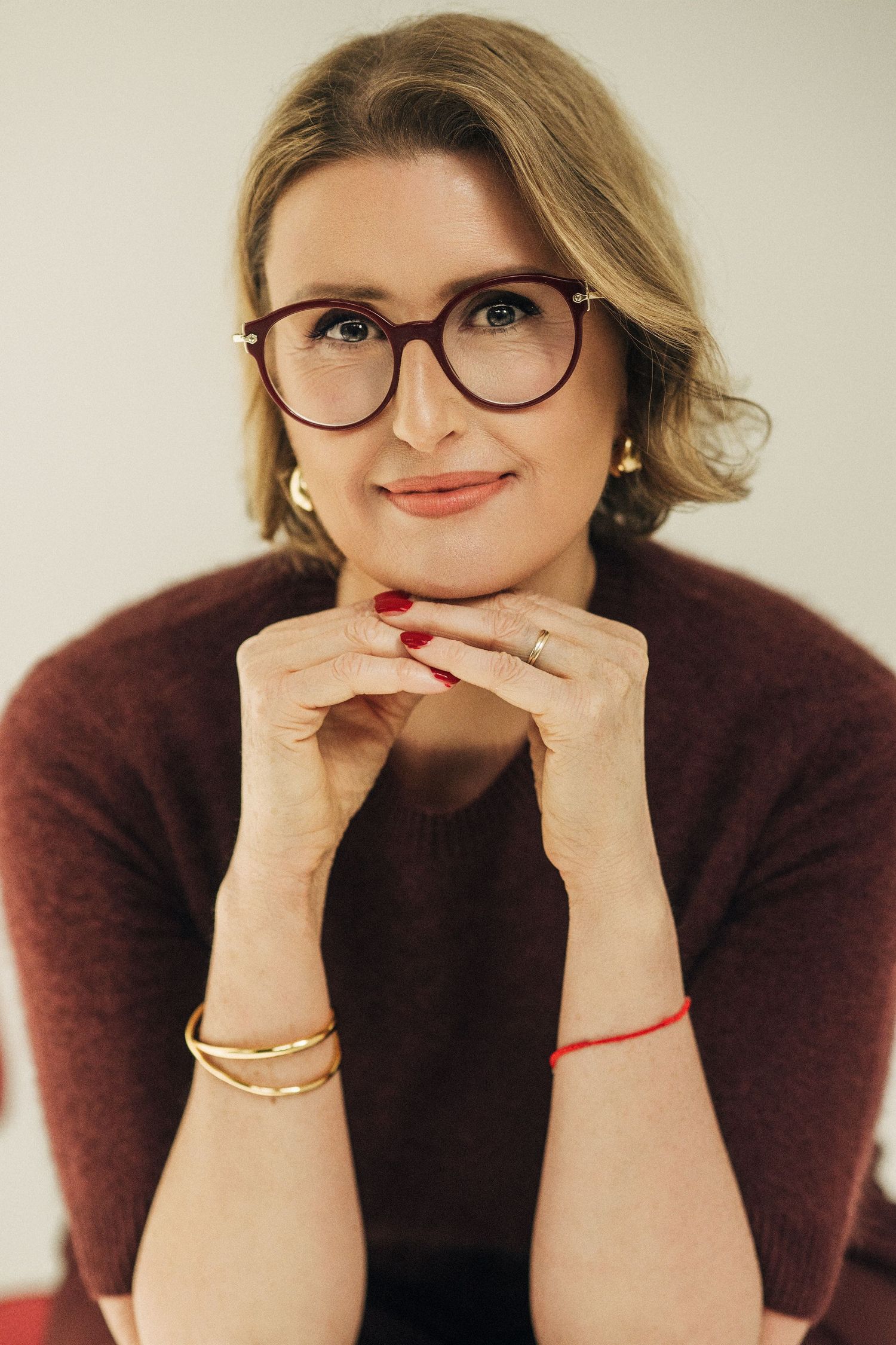 A series of four similar portraits showing someone wearing glasses and a burgundy sweater in different playful poses.