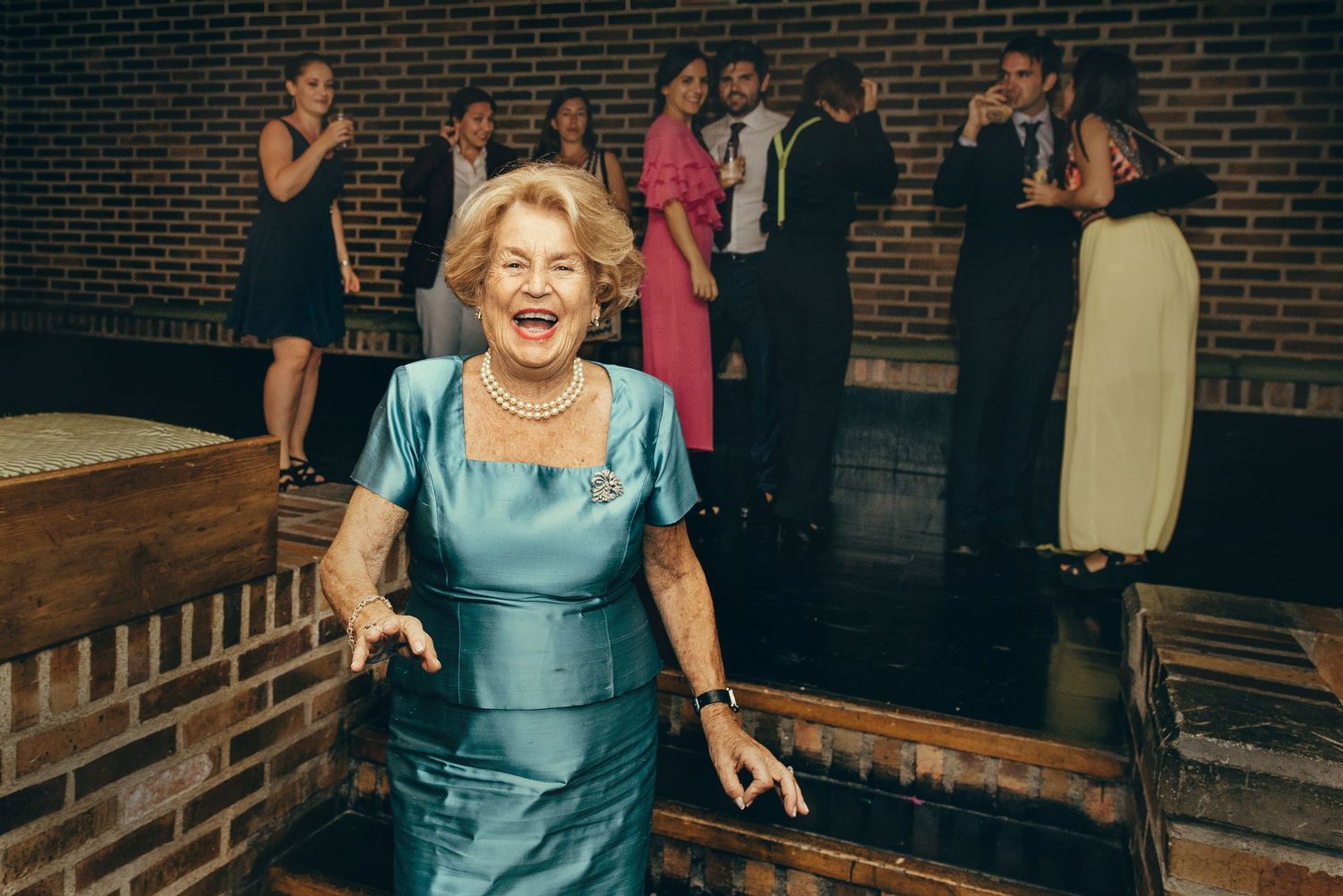 Dance party guests enjoying themselves on a dance floor with brick walls in the background.