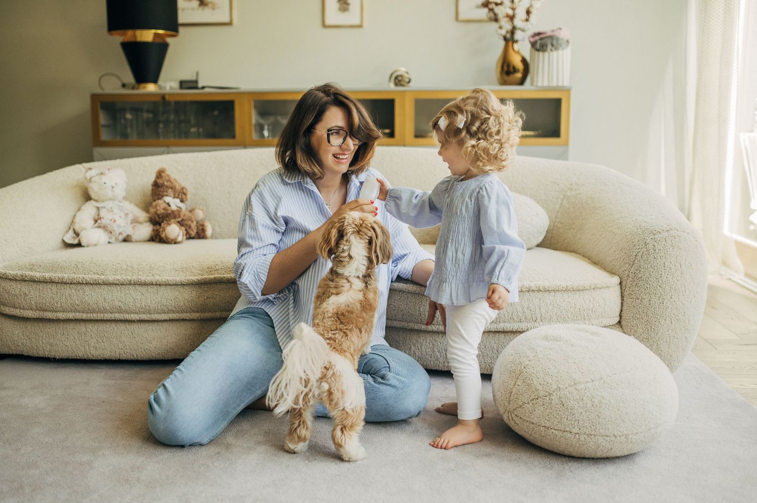 People interacting with stuffed animals on a couch in a cozy living room setting.