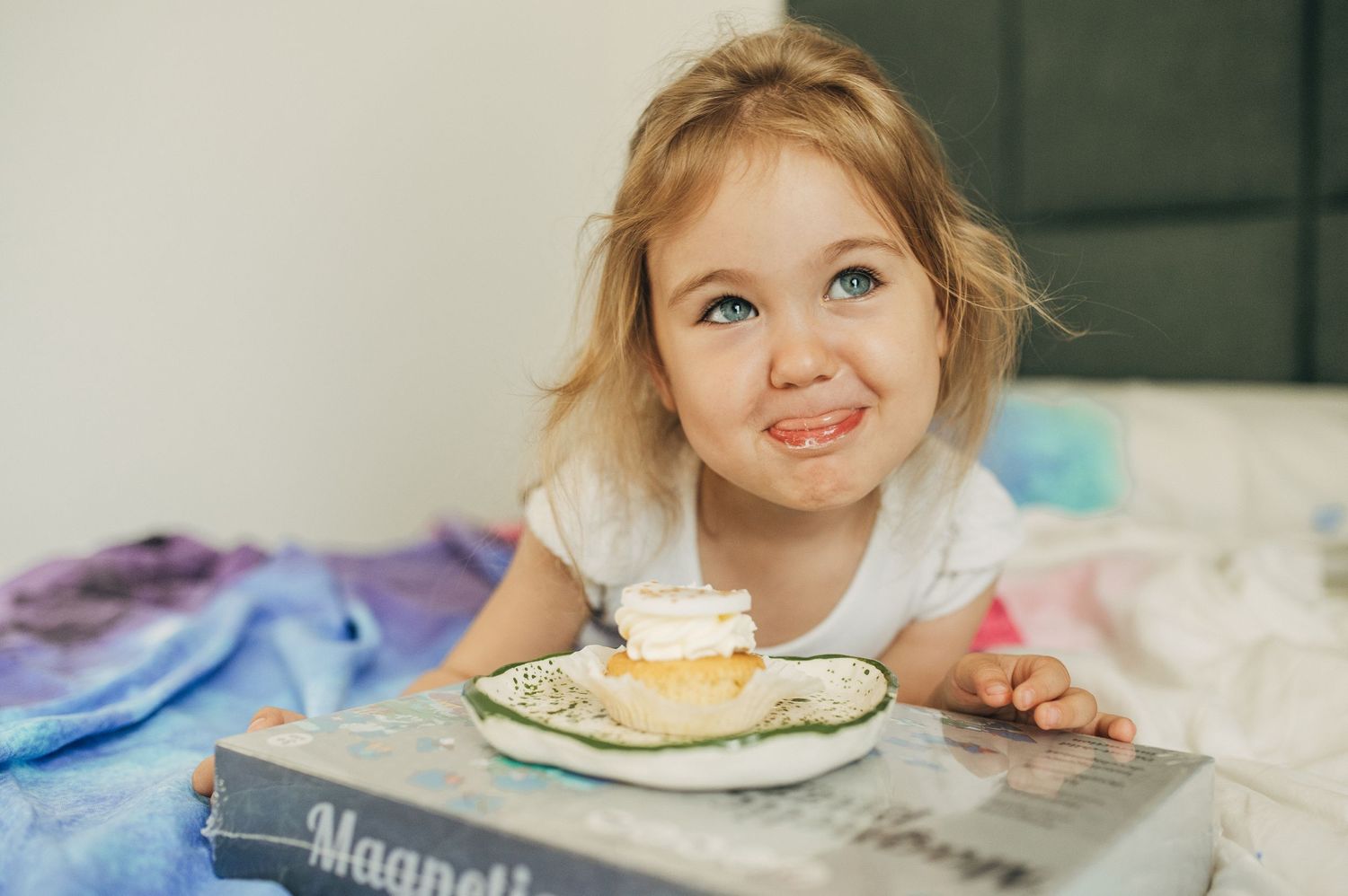 Child having snacks and enjoying treats at a white table.