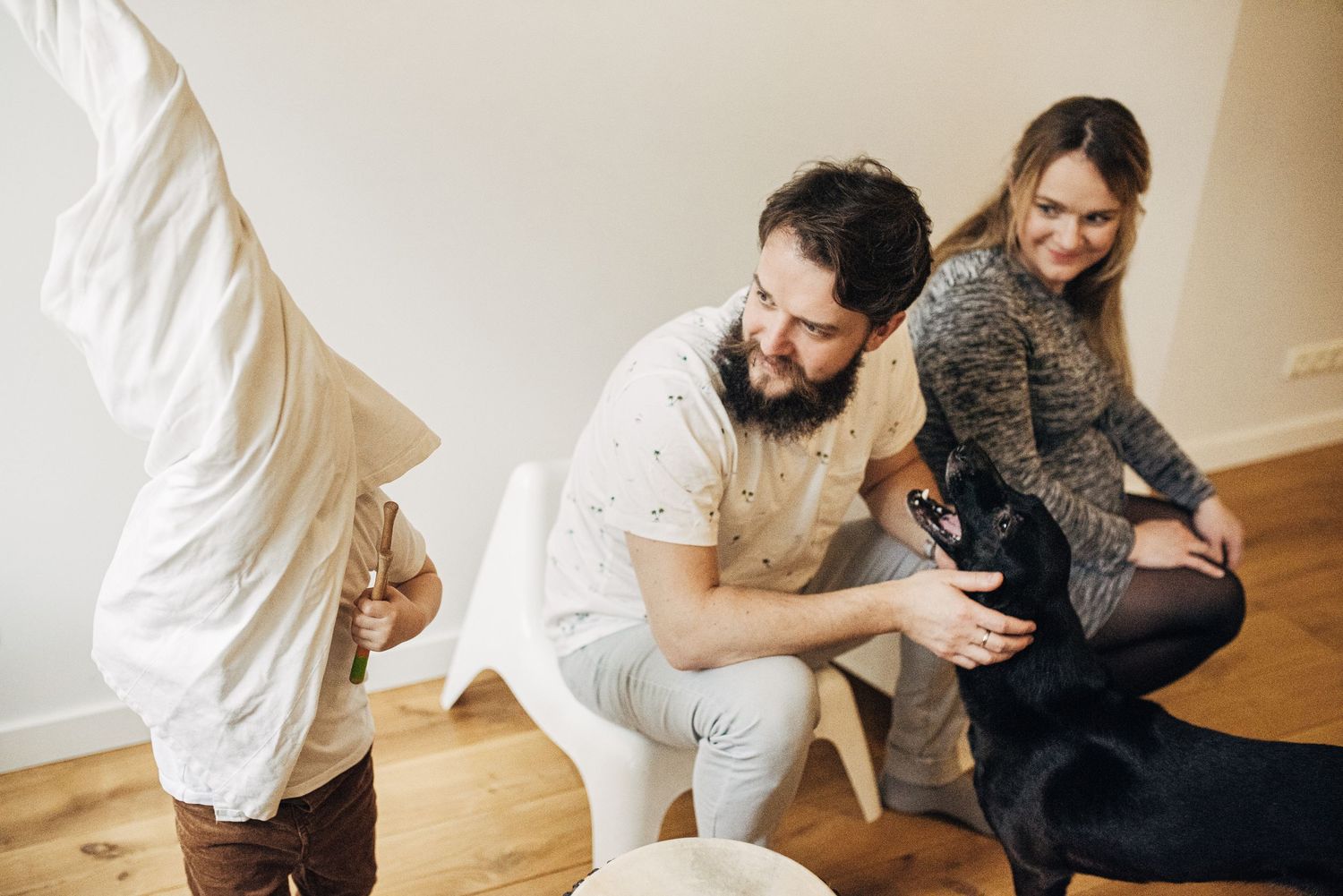 Family members sitting together on wooden floor in casual home setting.