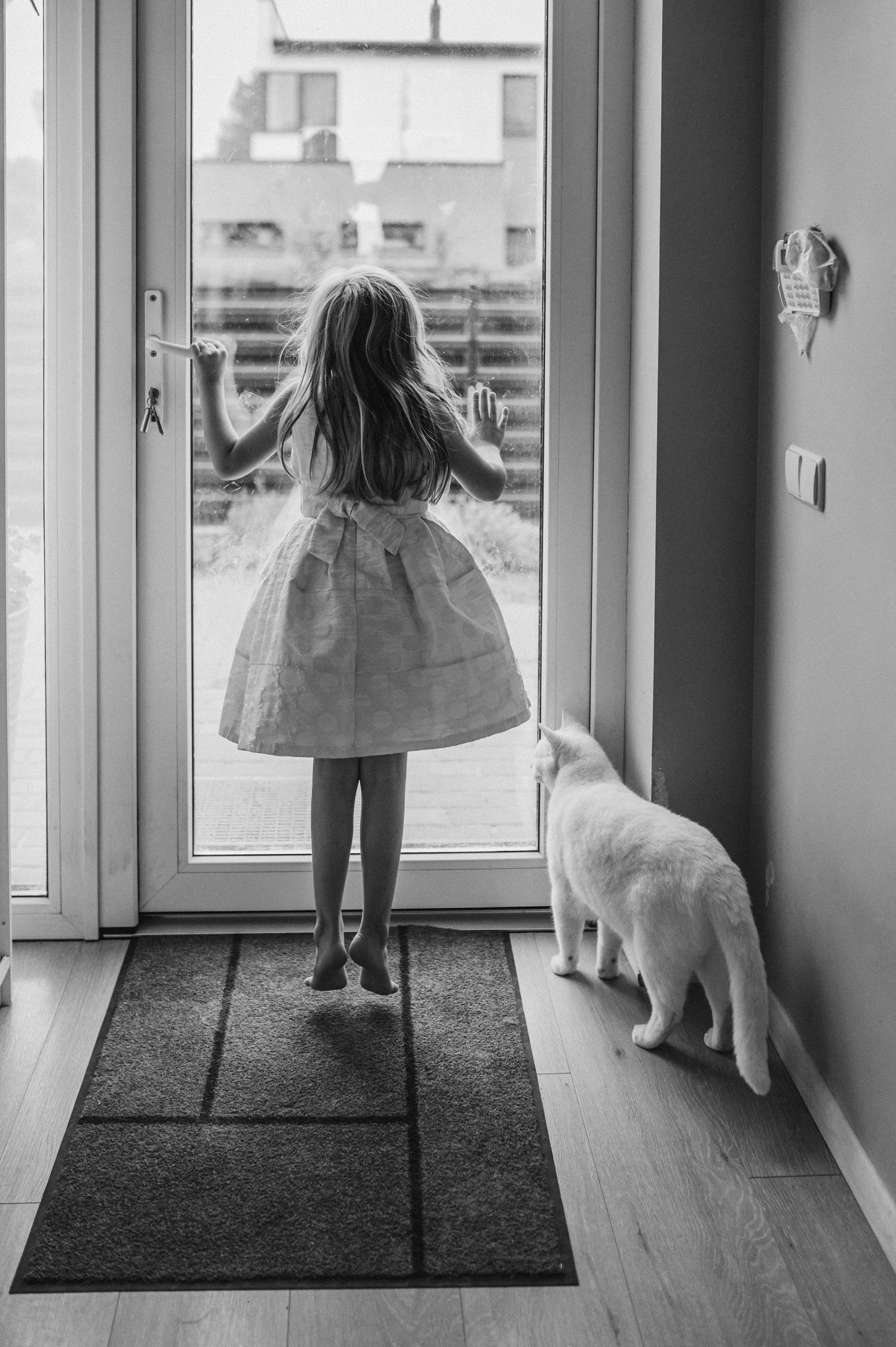 Black and white series of silhouettes looking out glass doors.