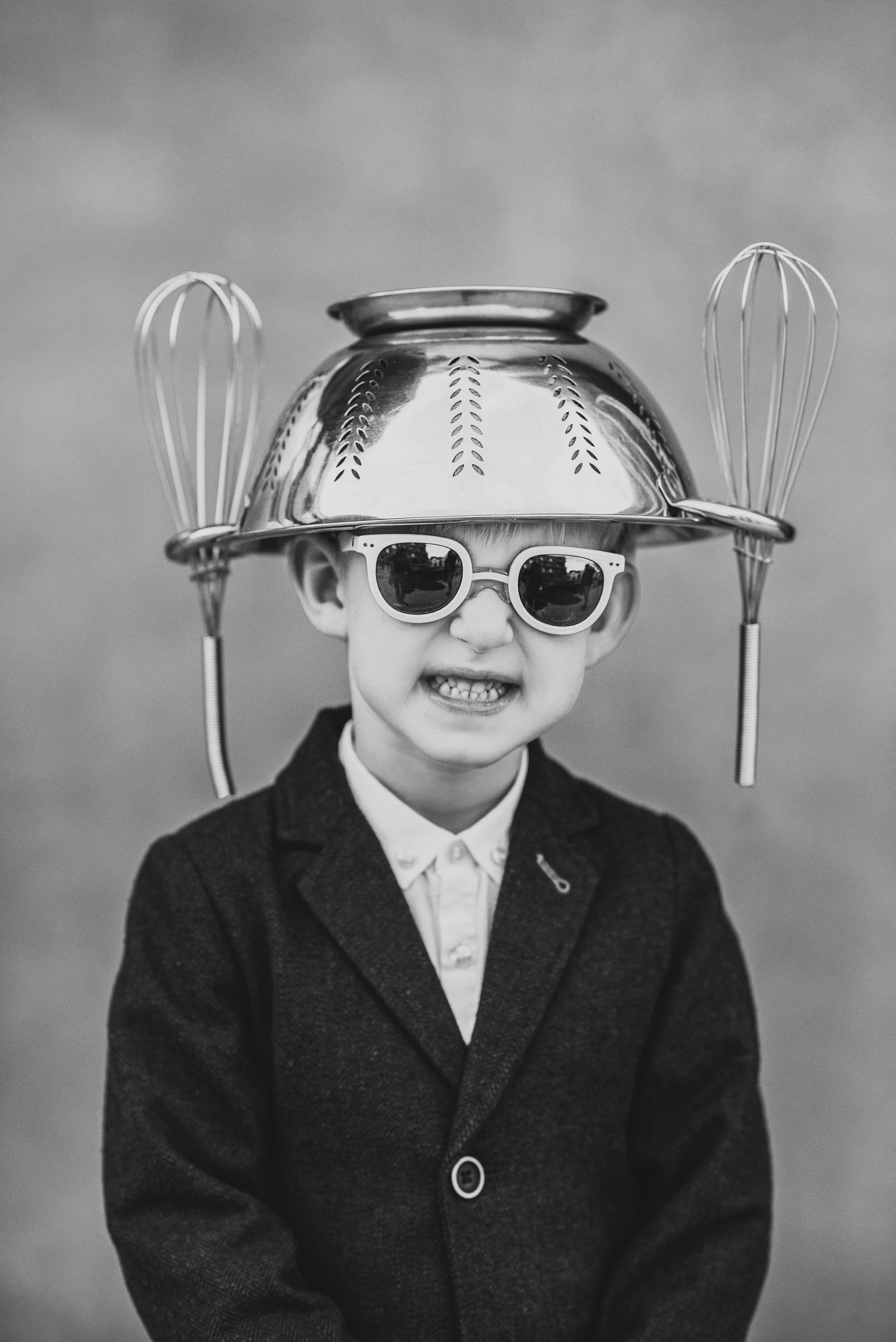 Creative portrait with a colander and whisks as a playful hat accessory with sunglasses.