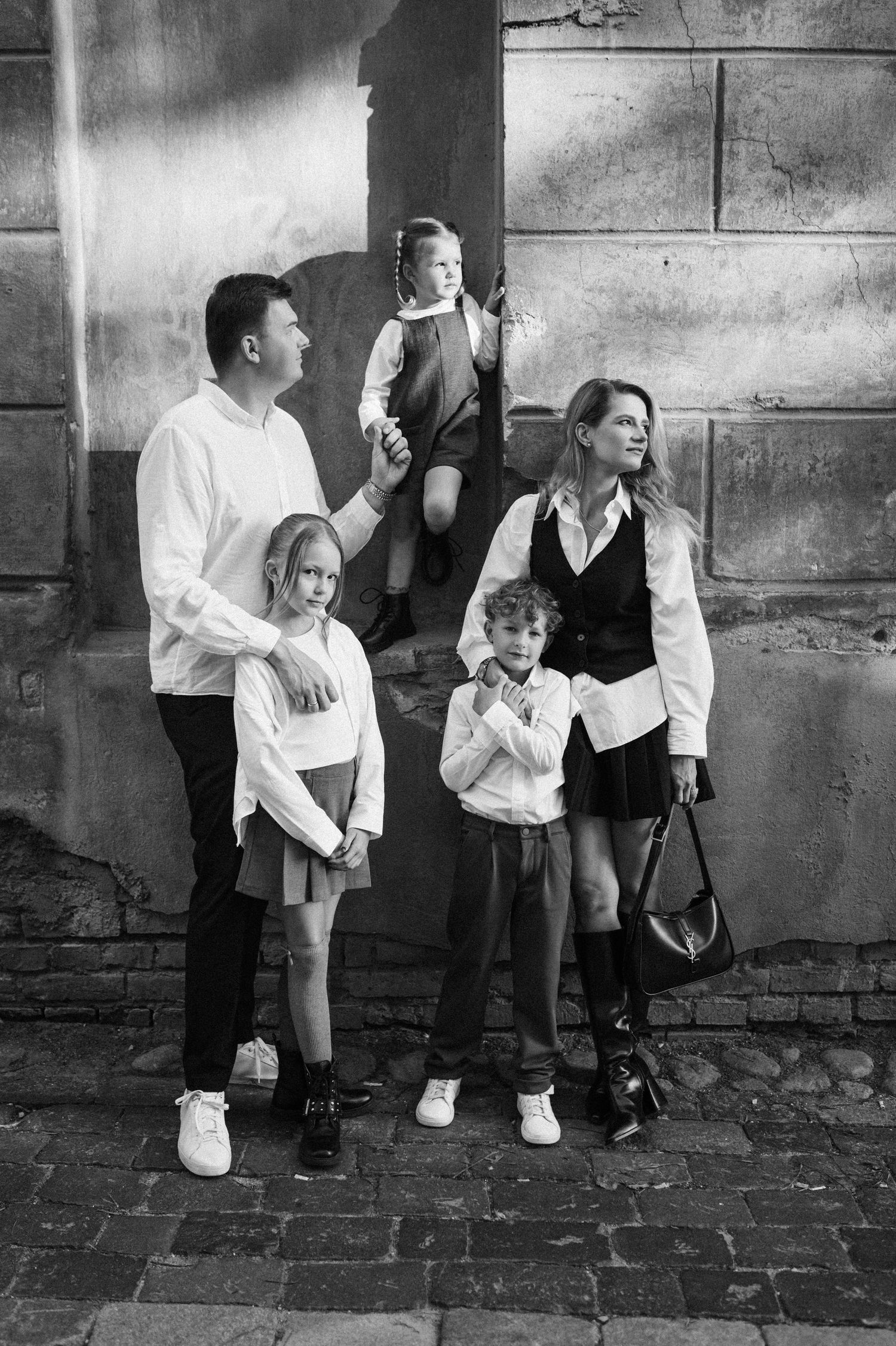Black and white portrait of children standing against a textured stone wall.