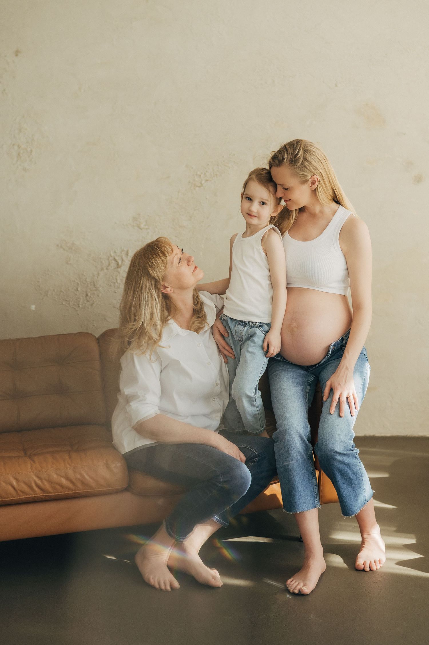Intimate maternity photoshoot in a minimalist indoor setting with natural window light.