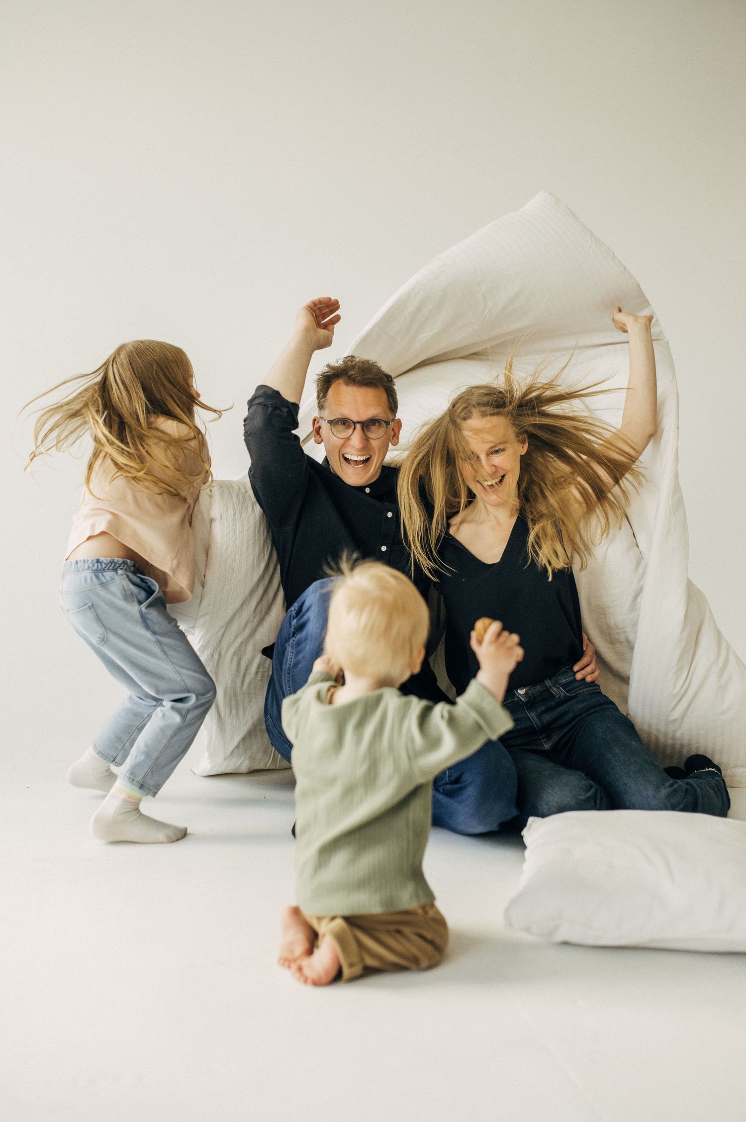 A playful sequence of people having a pillow fight on a white couch, captured in a minimalist style.